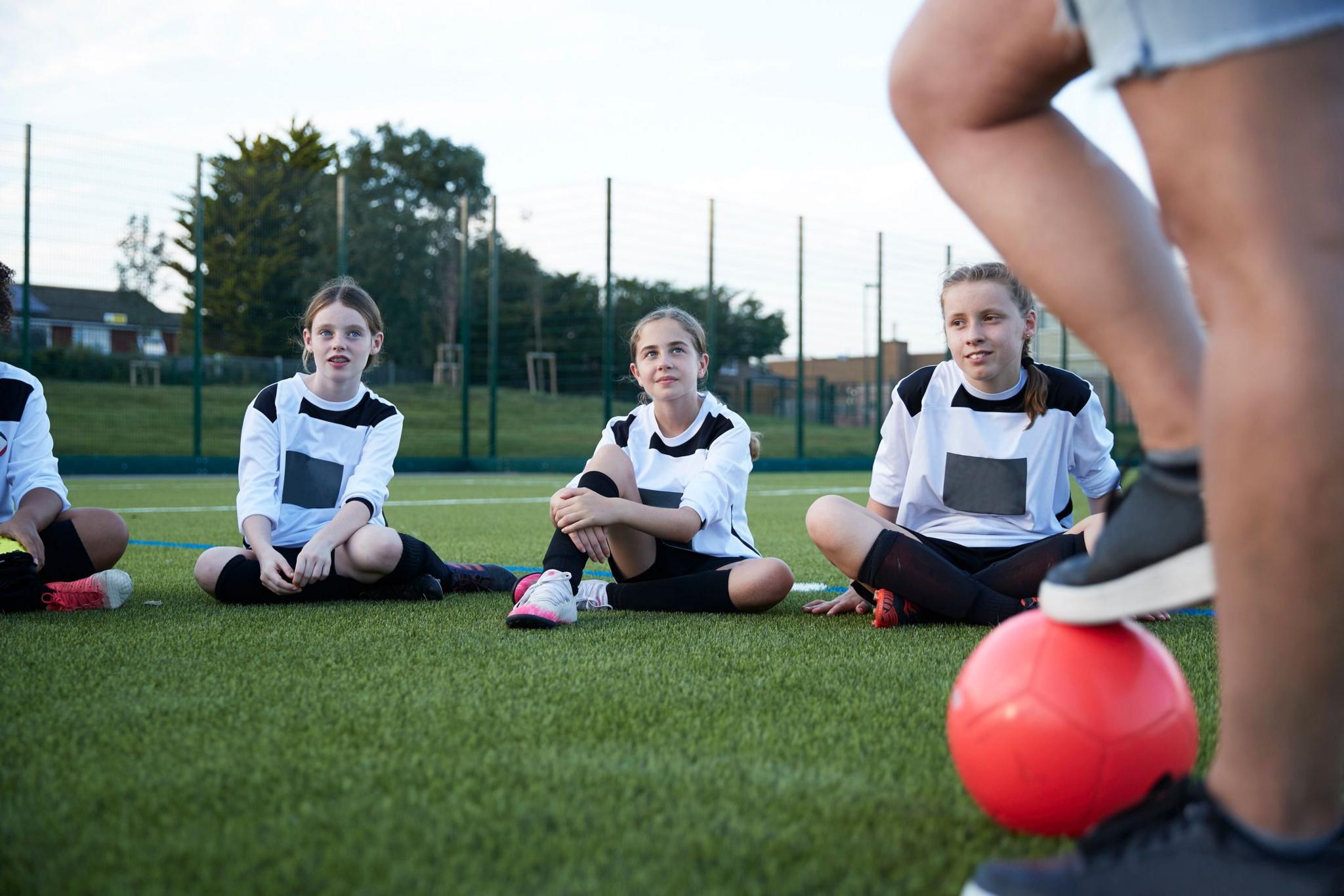 Football team of girls sitting in field during training.