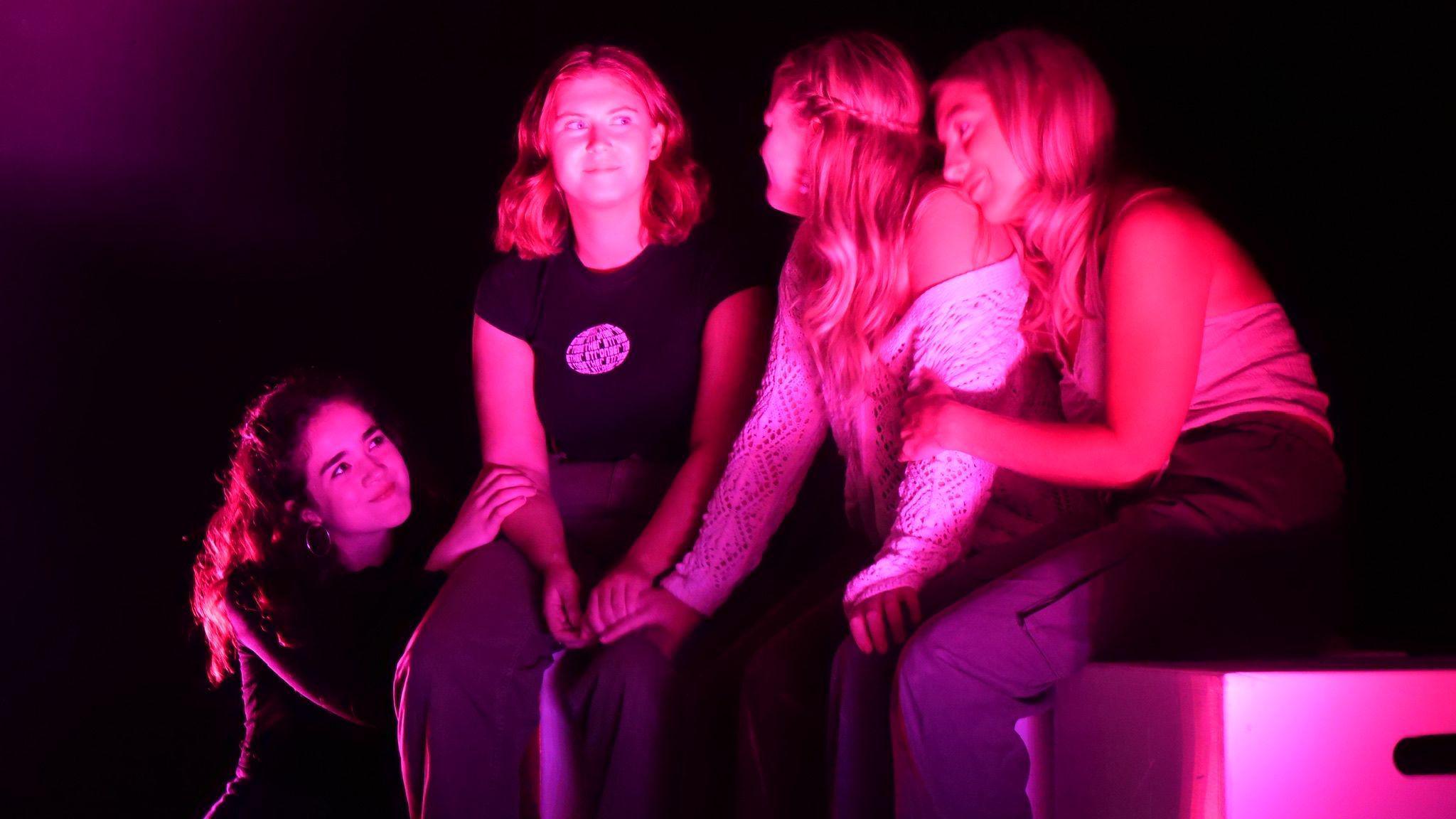 Annie McIlwaine, Orla Graham, Ellen Andrews, and Leah Williamson sit on stage in pink lighting