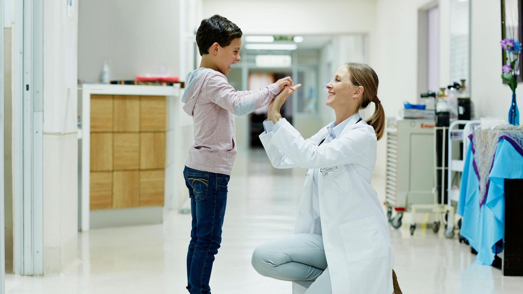 Boy high-fiving doctor in corridor 