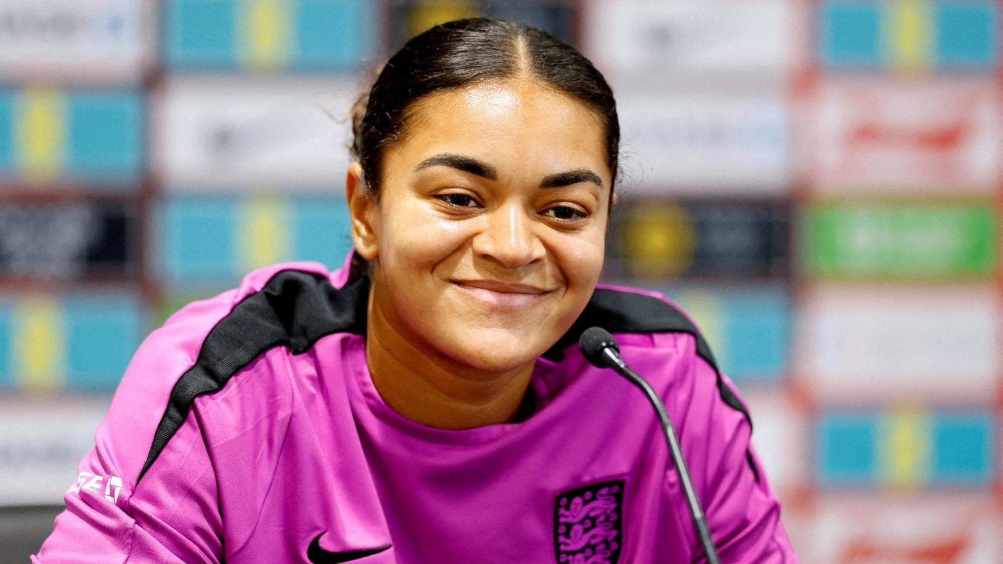England footballer Jess Carter, wearing a purple England t-shirt, speaks at a press conference.