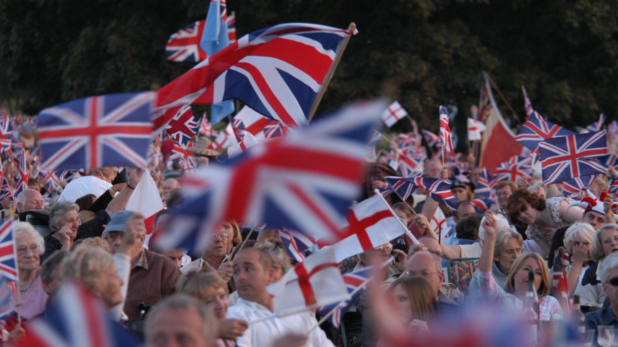 A large crowd of people waving flags at a Proms event.