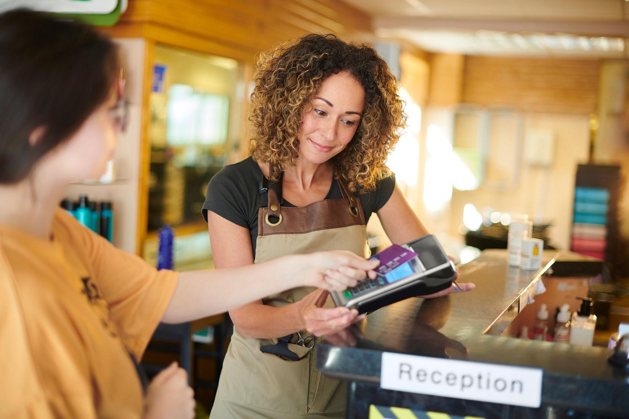 A woman receives a card payment from a customer in a salon