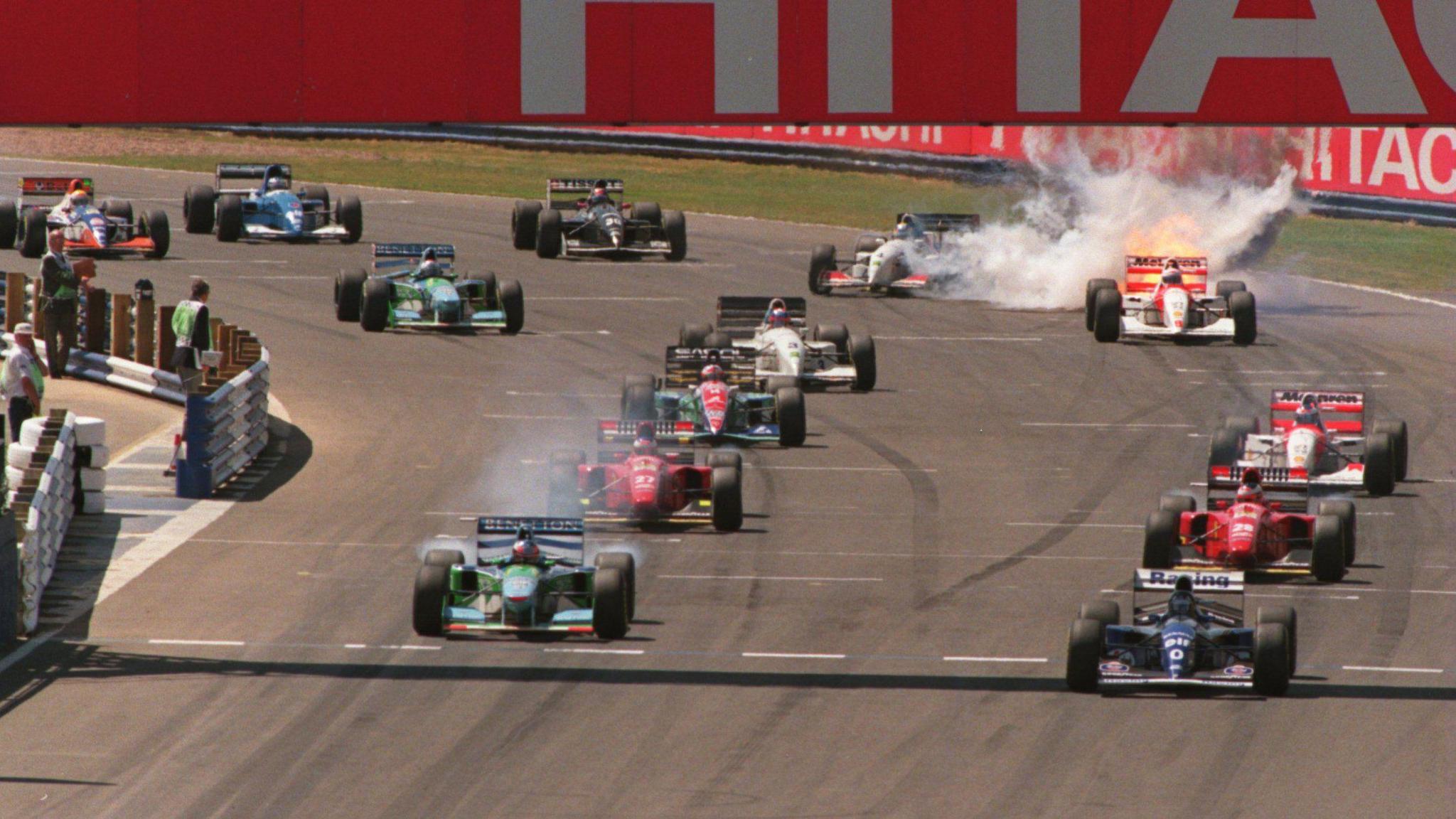The cars move away at the start in 1994 with Williams' Damon Hill ahead of Benetton's Michael Schumacher as the engine on Martin Brundle's McLaren-Peugeot explodes in spectacular style