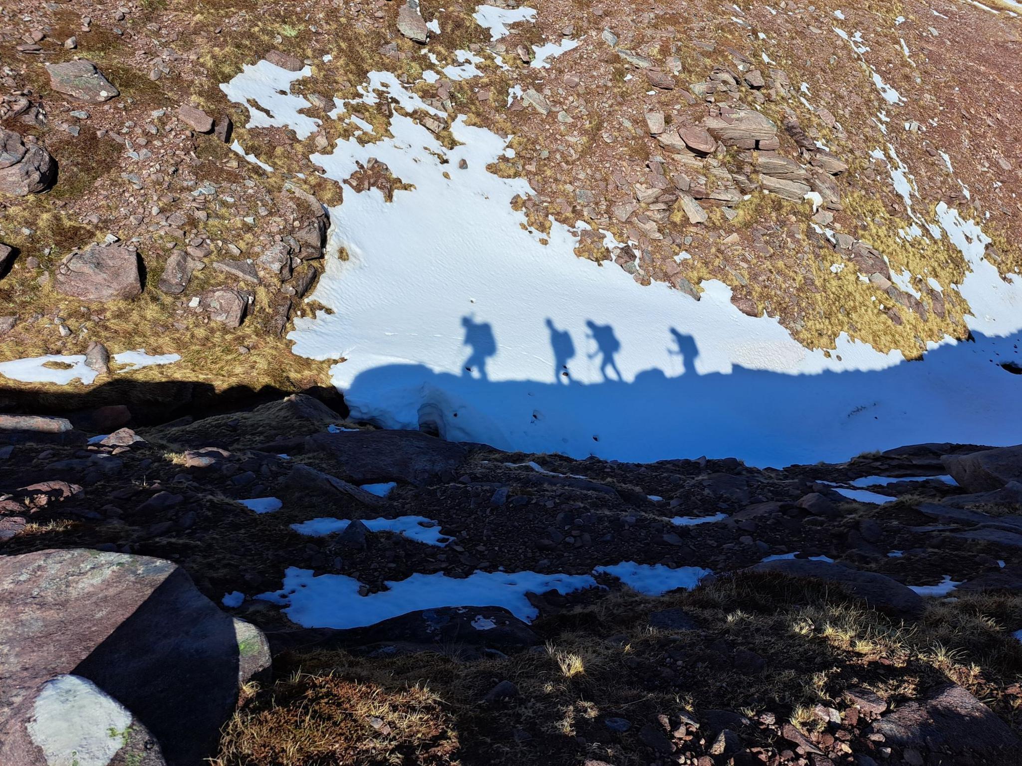 Shadow of four mountain climbers on the snow