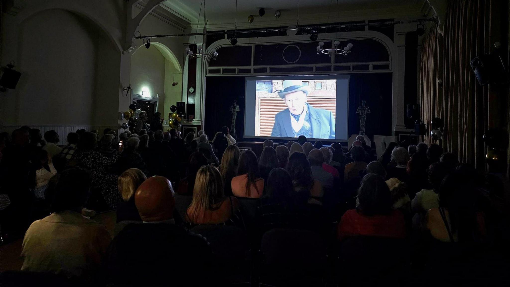 Crowd watch western on a projector screen