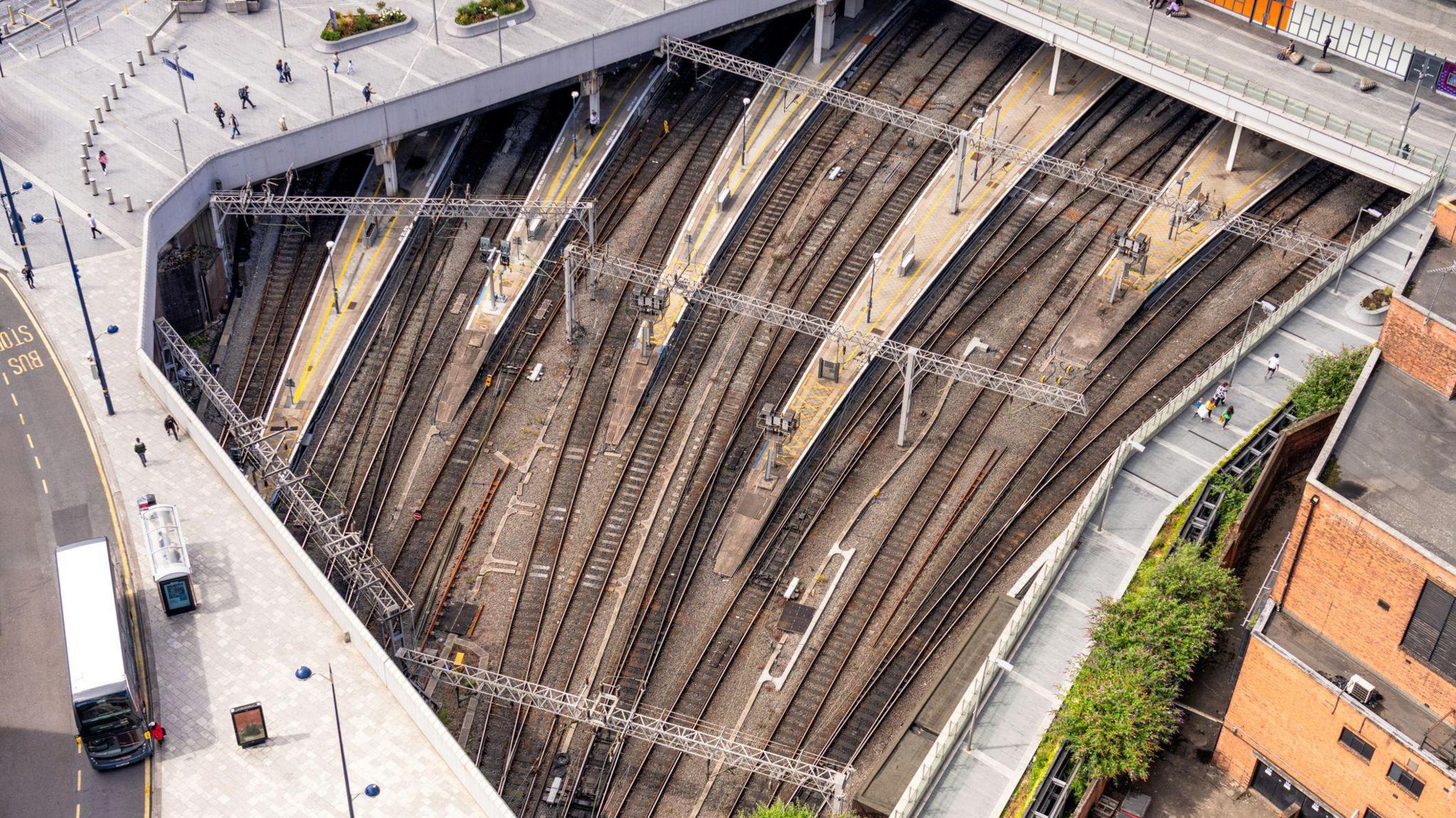 A view from above train tracks and the surrounding streets and pavements in Birmingham as the tracks separate in their approach to New Street Station.
