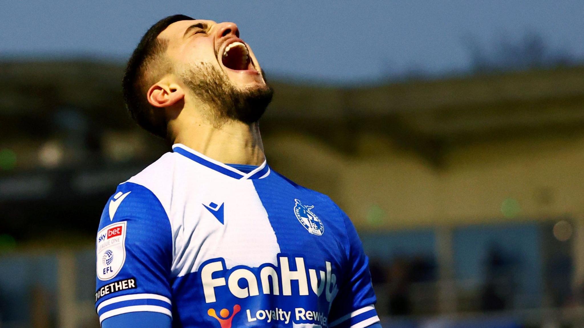 Bristol Rovers player Ruel Sotiriou shouts as he looks to the sky after scoring the third goal in Rovers' 3-1 win over Barnsley at the Memorial Stadium. It is after dark and the blurry main stand can be seen in the background