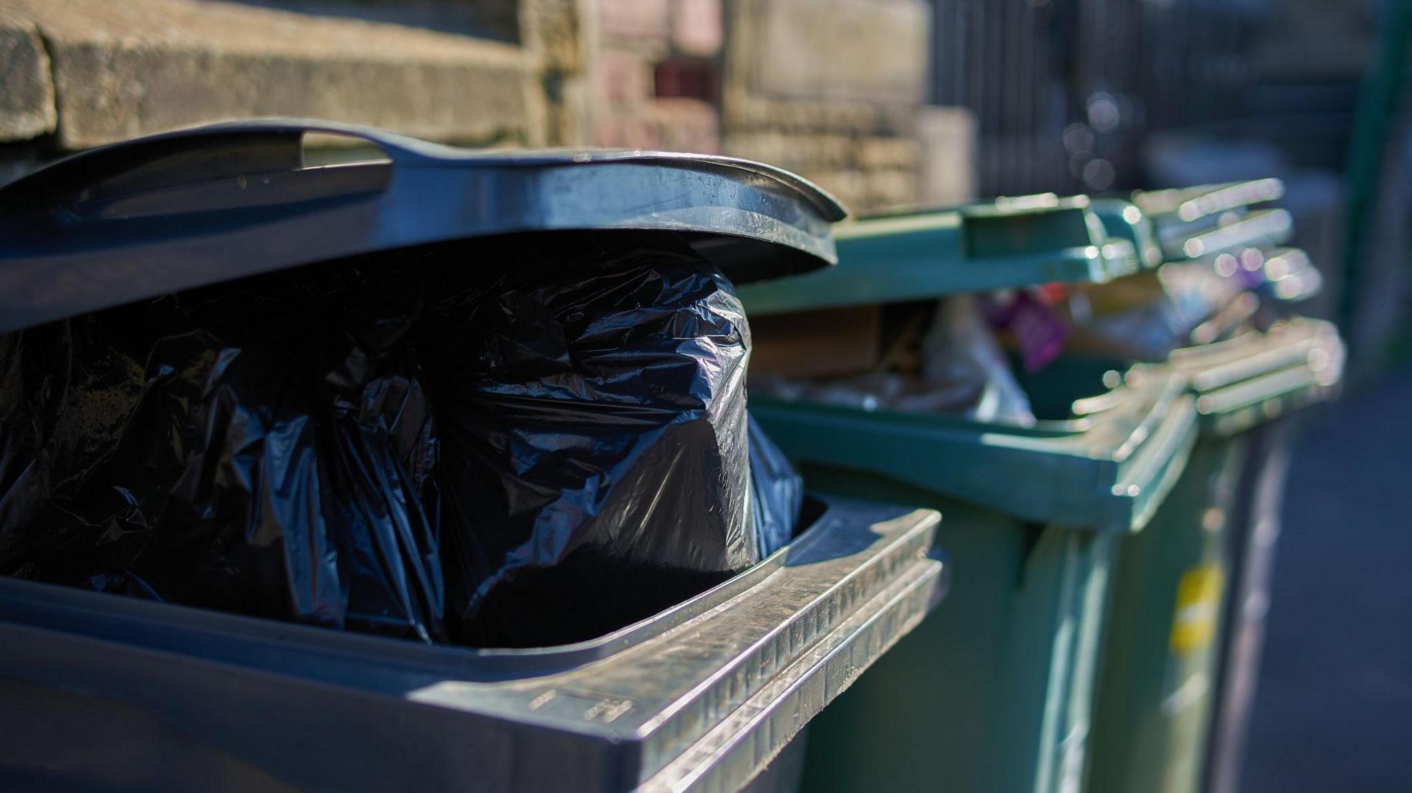 Black bags in and out of wheelie bins