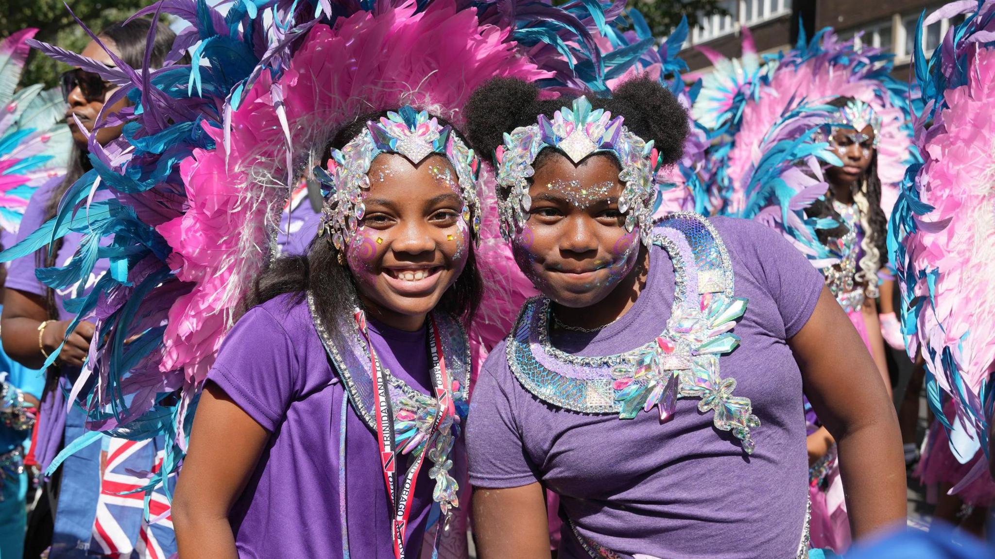 Two girls in pink and purple outfits pose during the Children's Day Parade