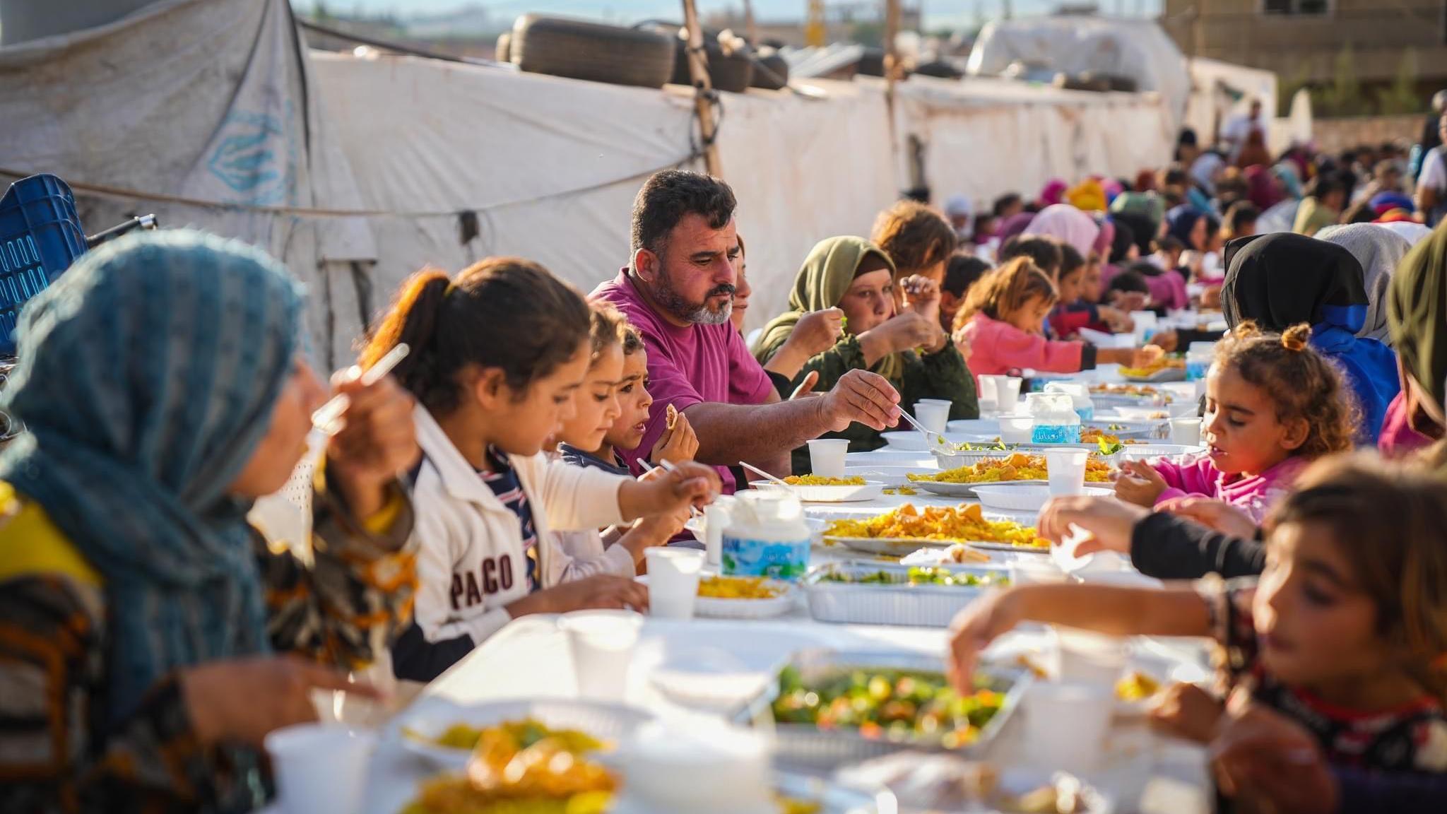 A gathering of people eating food outside 