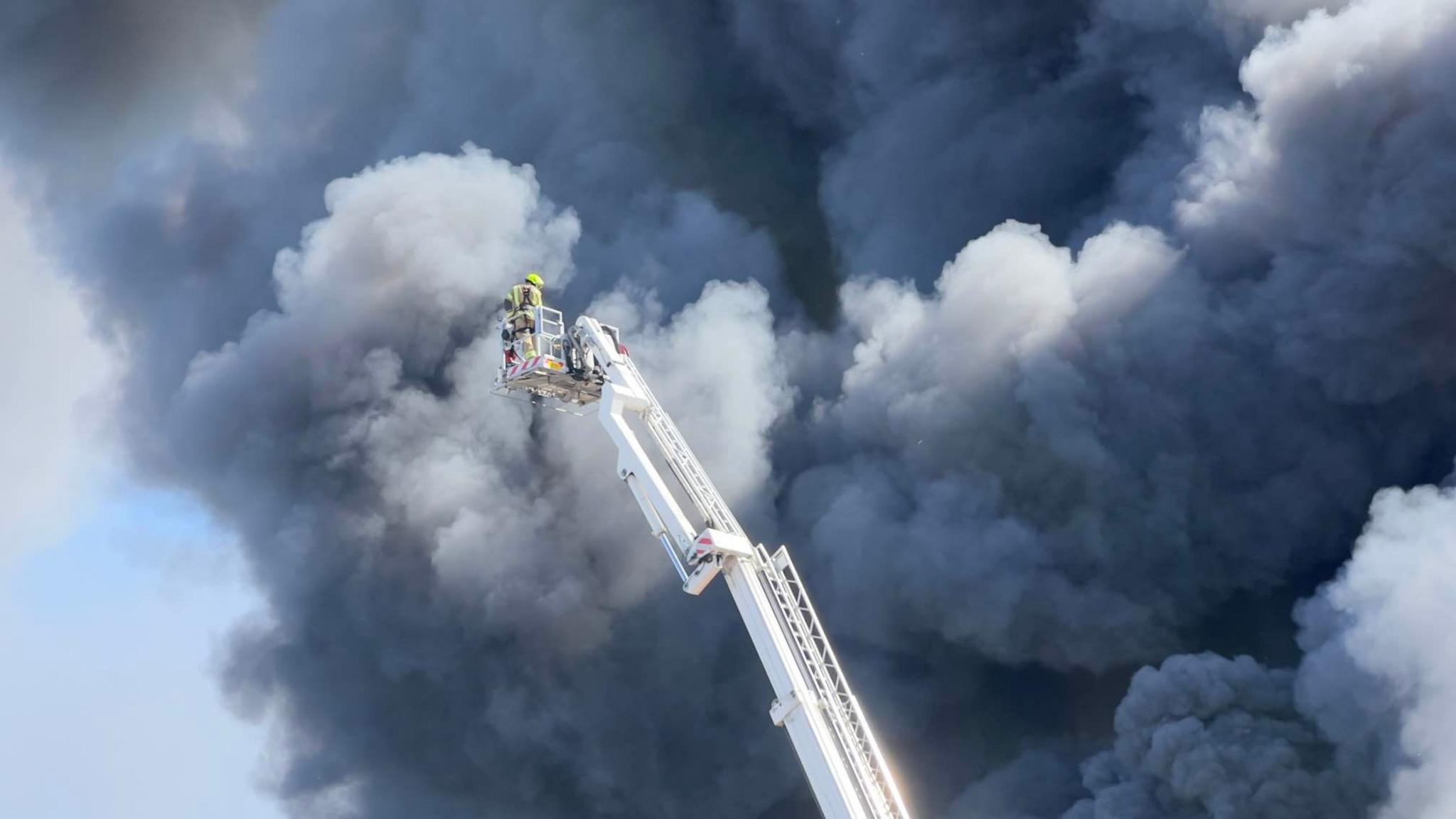 A firefighter using an aerial ladder to tackle the fire from above