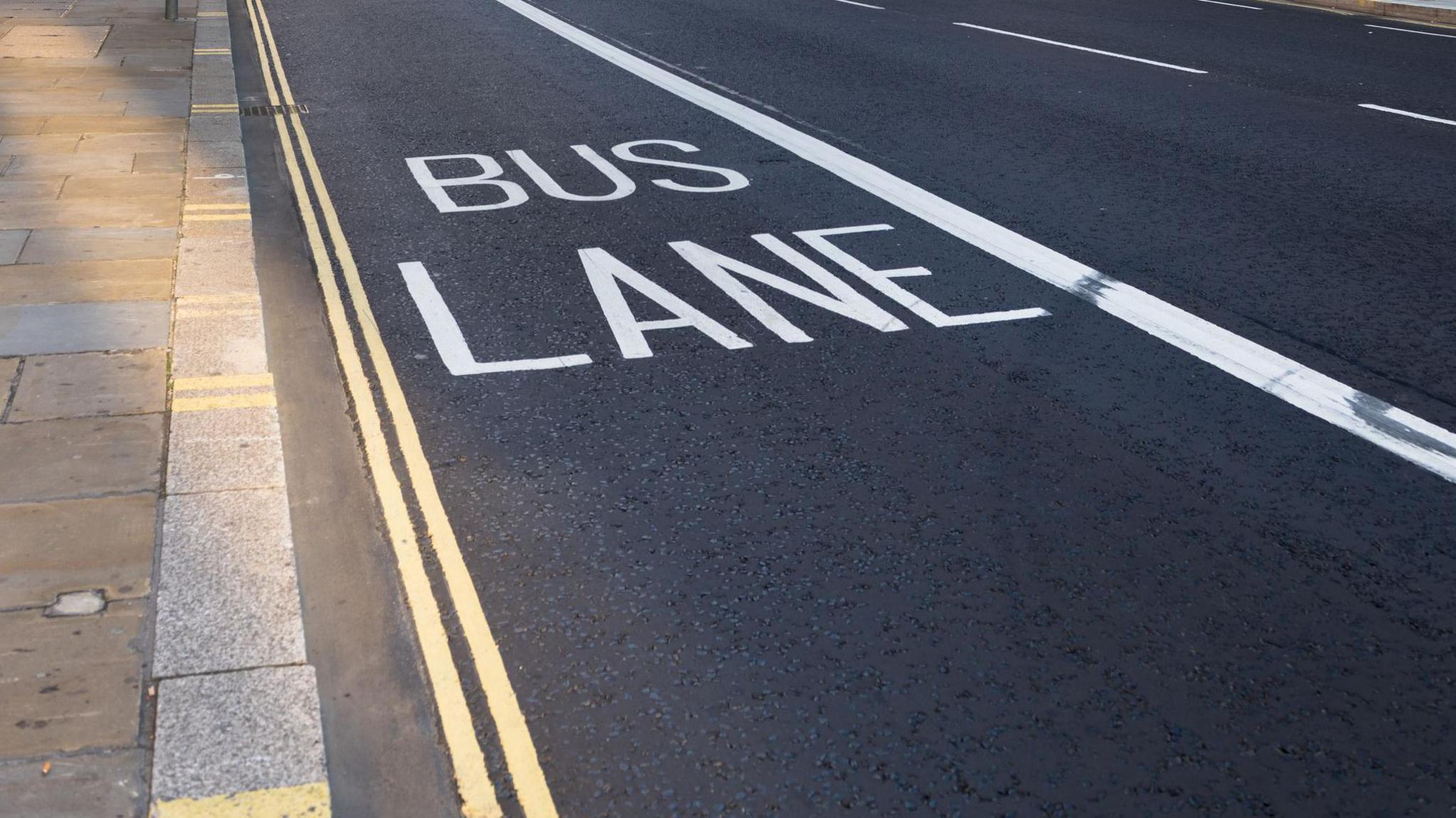 a road with white bus lane markings, the words bus lane are visible in capital letters in the middle of the lane