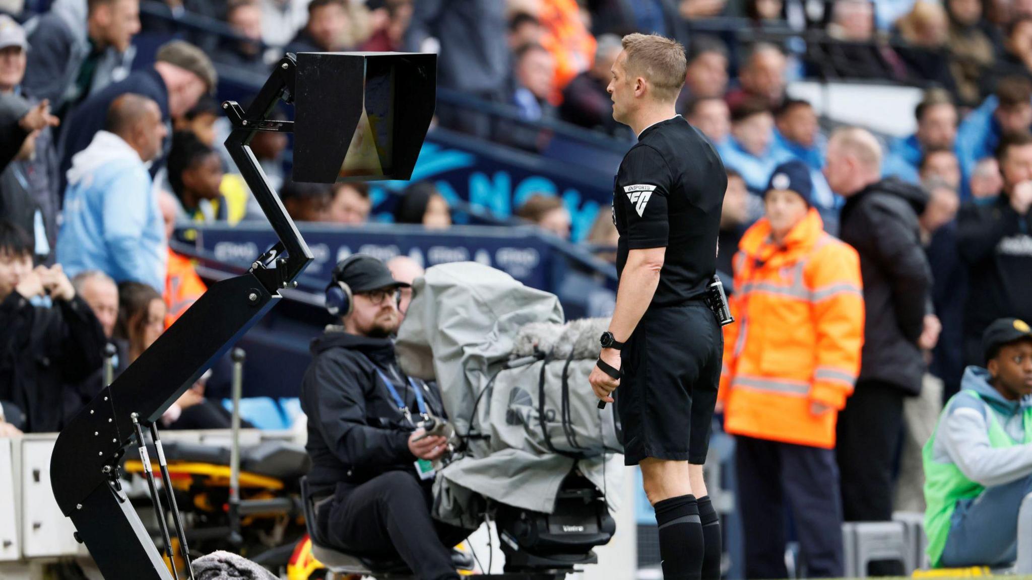 Referee Craig Pawson views the VAR screen at a football stadium