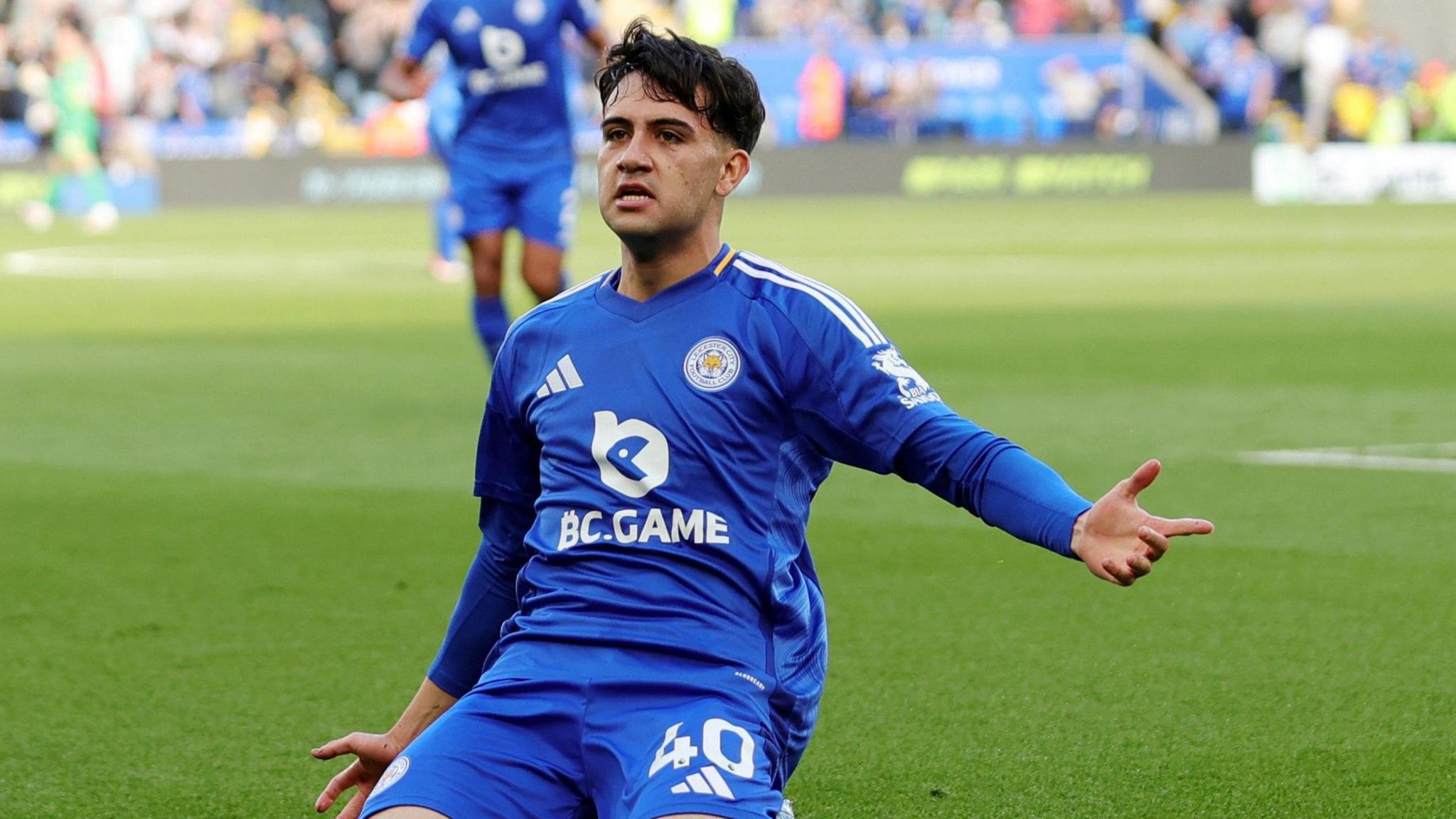 Facundo Buonanotte, wearing Leicester's blue home kit, slides on his knees with his left arm outstretched to celebrate his goal against Bournemouth.