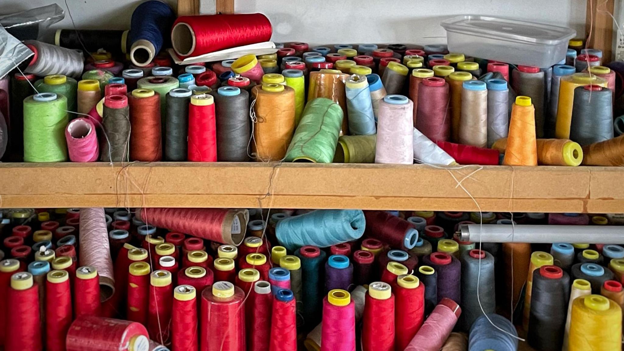 Reels of coloured thread on a shelf  