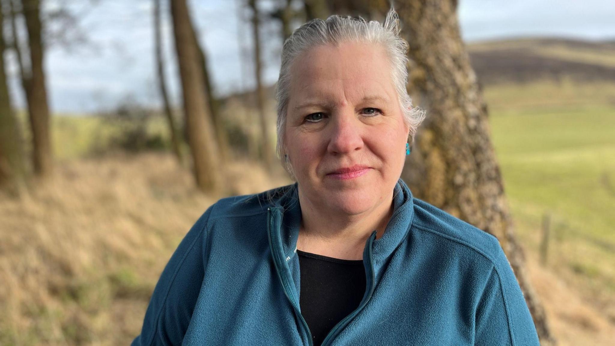 Scotland's chief veterinary officer Sheila Voas. She is looking directly at the camera, wearing a teal fleece. There are trees and fields in the background.