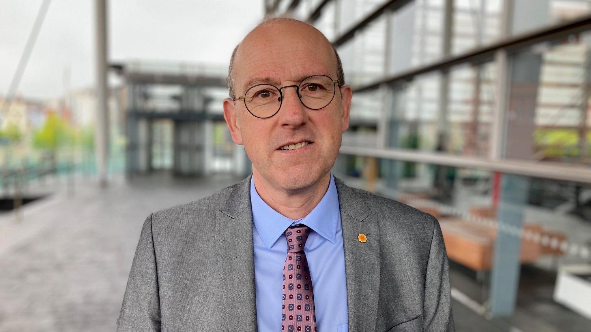 Llyr Gruffydd, MS - chair of the Senedd's climate change, environment and infrastructure committee - standing in front of the Senedd.