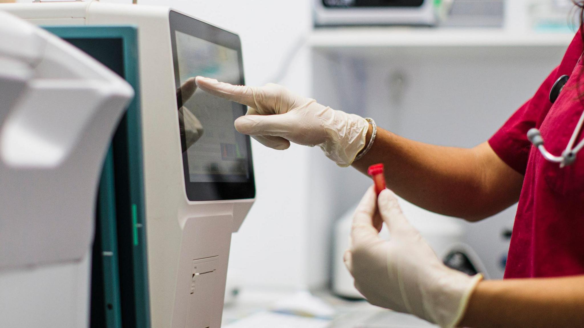 A female laboratory technician looks at the results of a blood test on a computer, stock image.