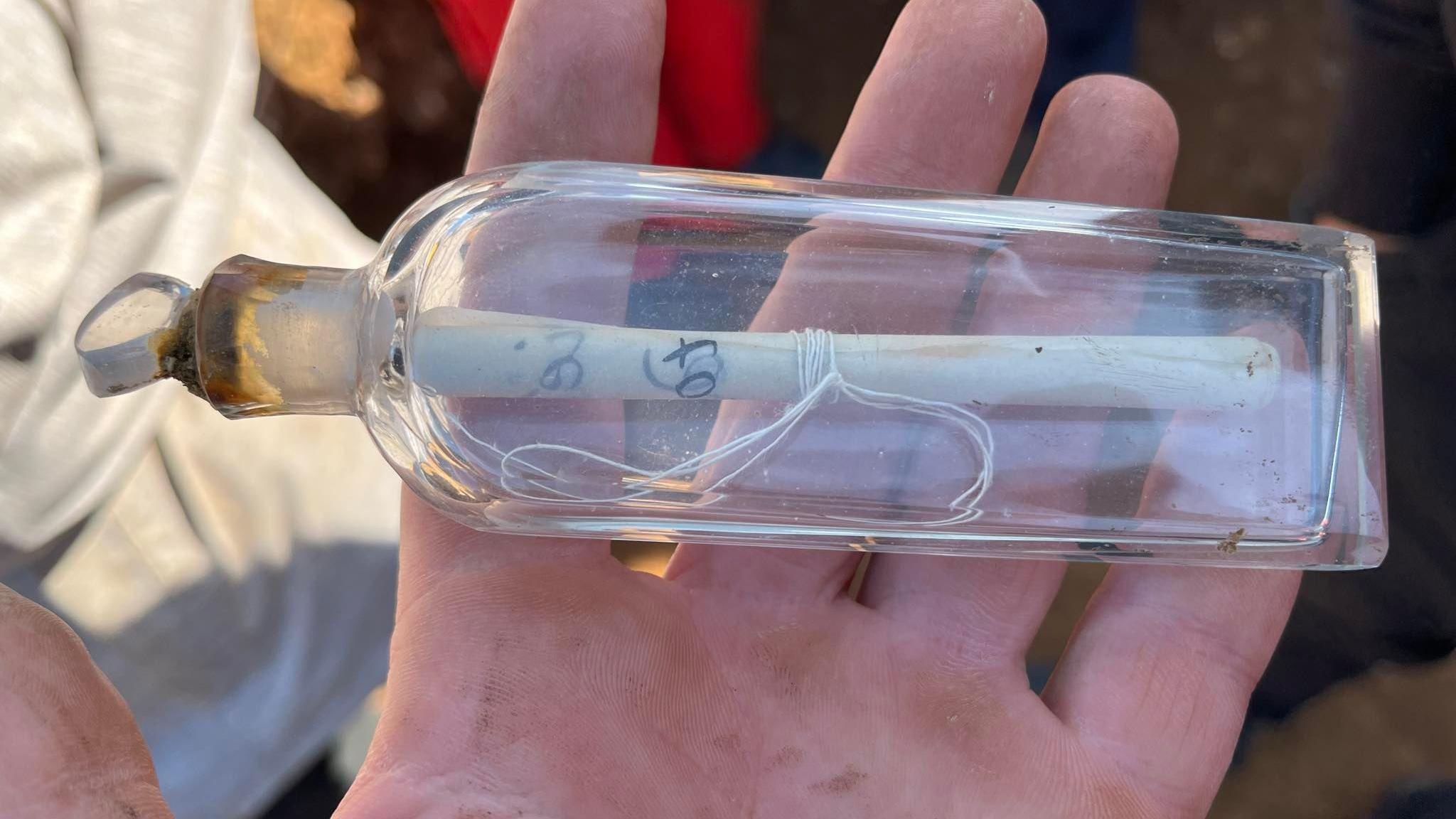 Glass bottle with a message from archaeologist rolled up and tied with string