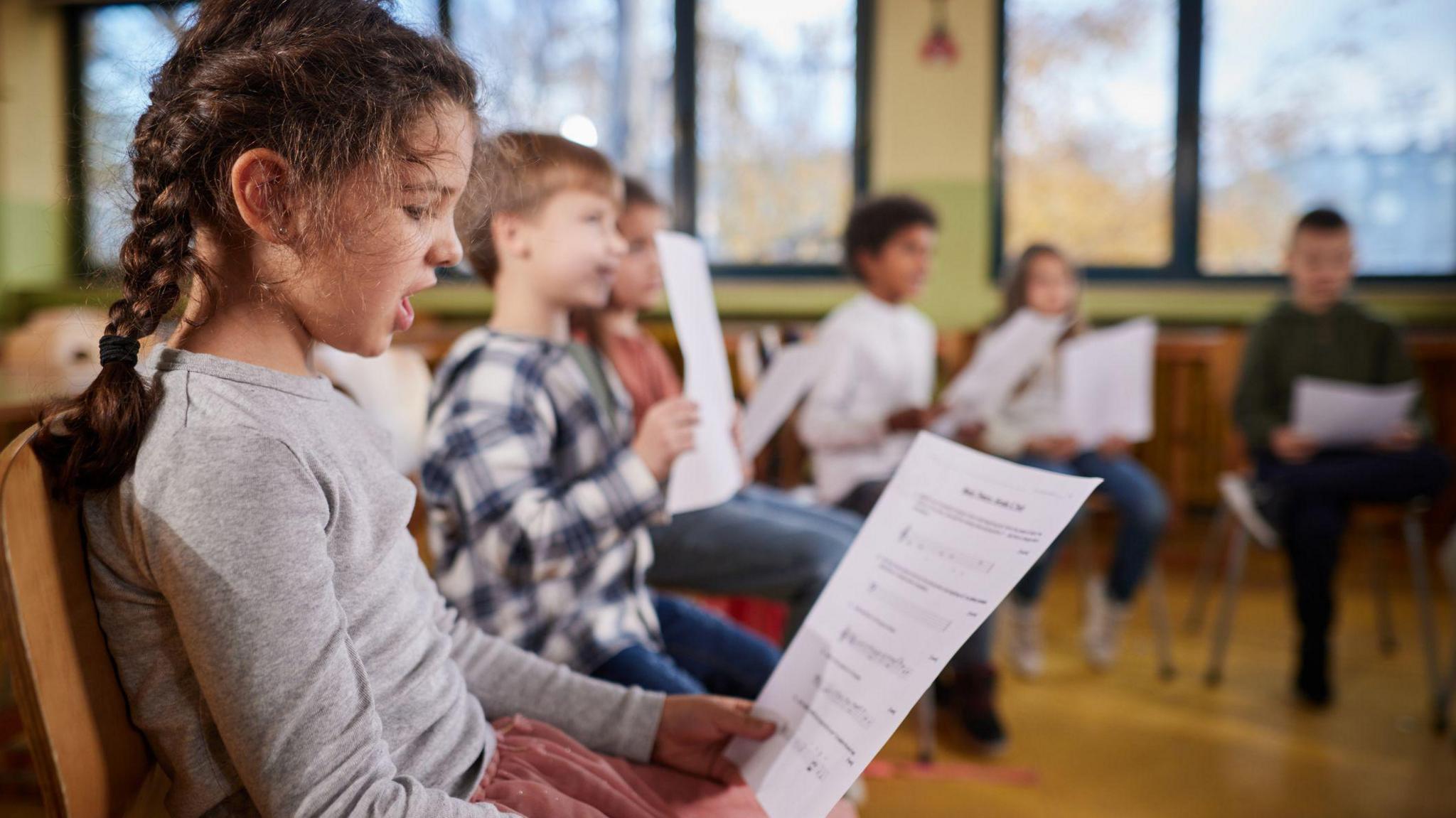 a girl practicing singing reading sheet music