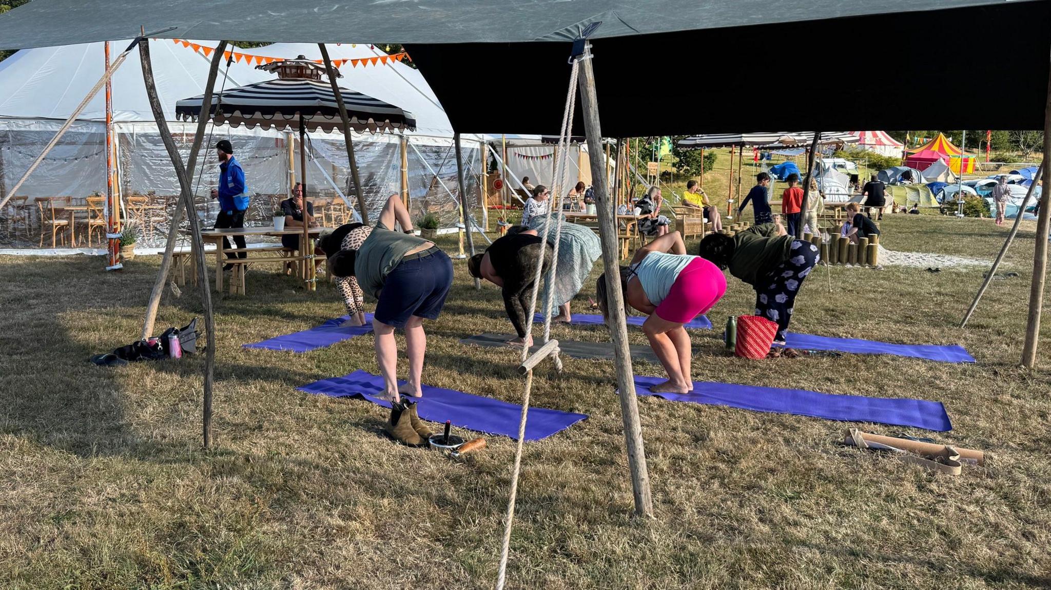 A group of woman doing yoga under a large gazebo.