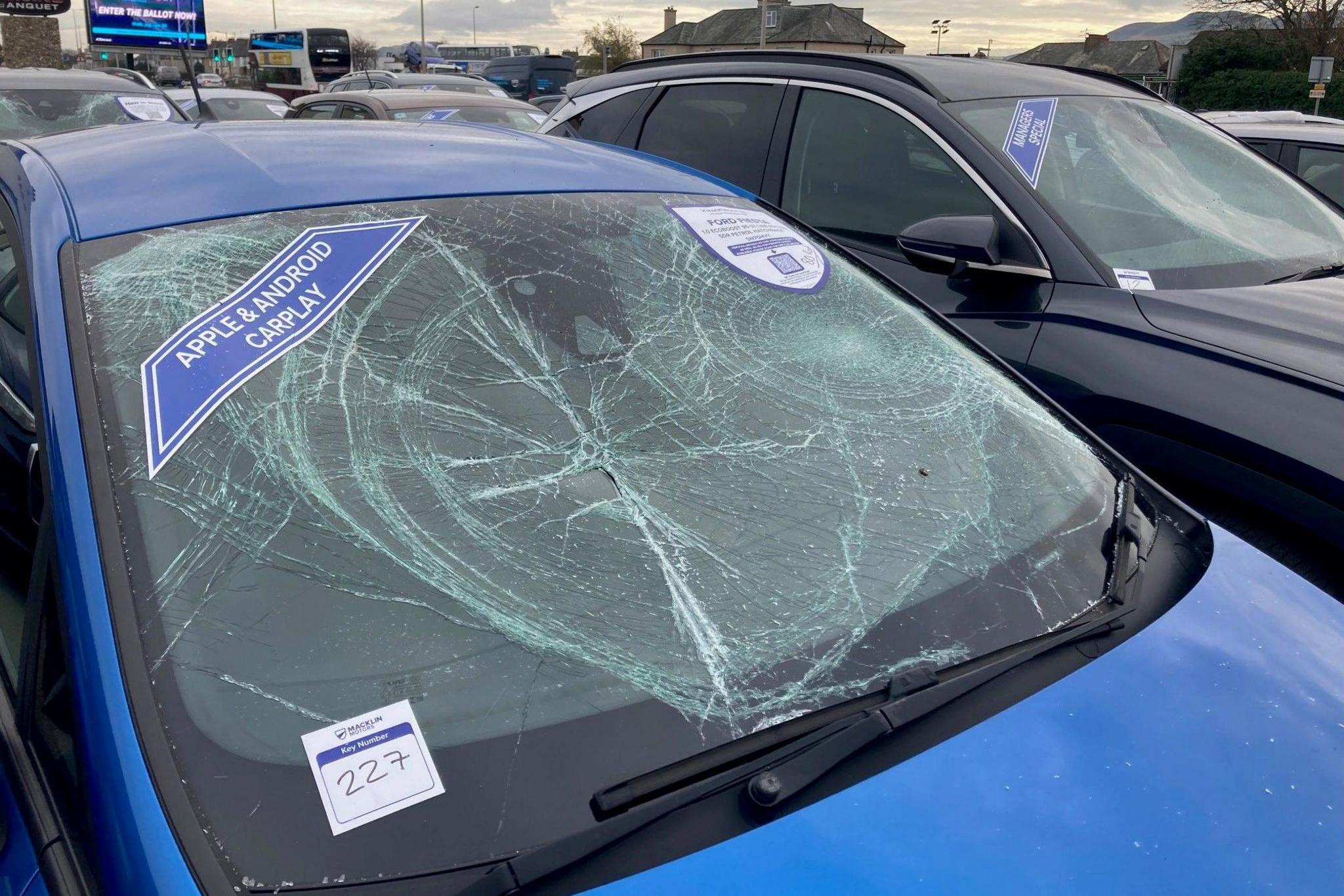 A blue car parked at the Macklin Motors Hyundai car dealership - the windscreen remains in place but is completely smashed
