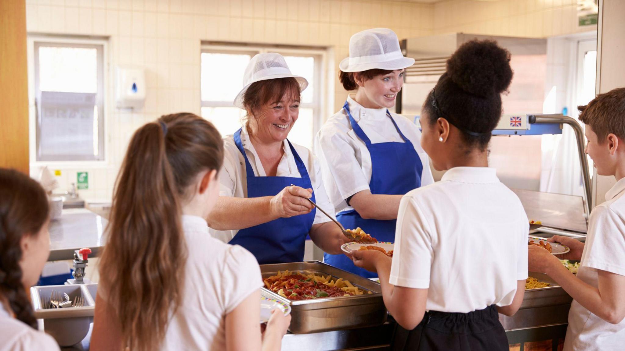 School canteen staff dishing out meals to pupils