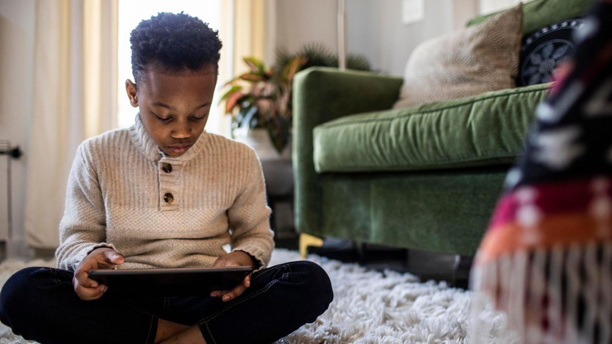 A boy looking down at a tablet