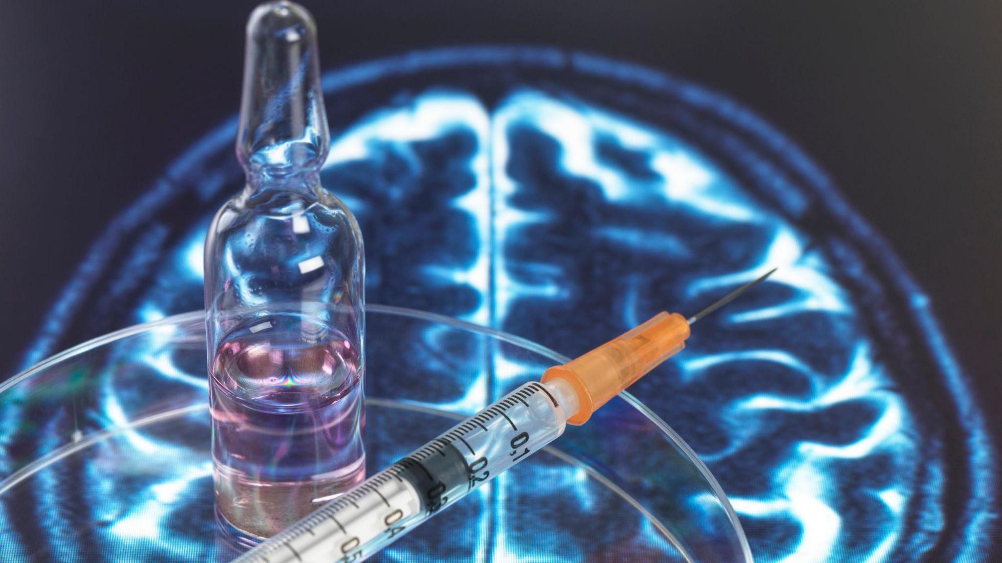 Glass vial and injection needle sitting on an image of someone's brain