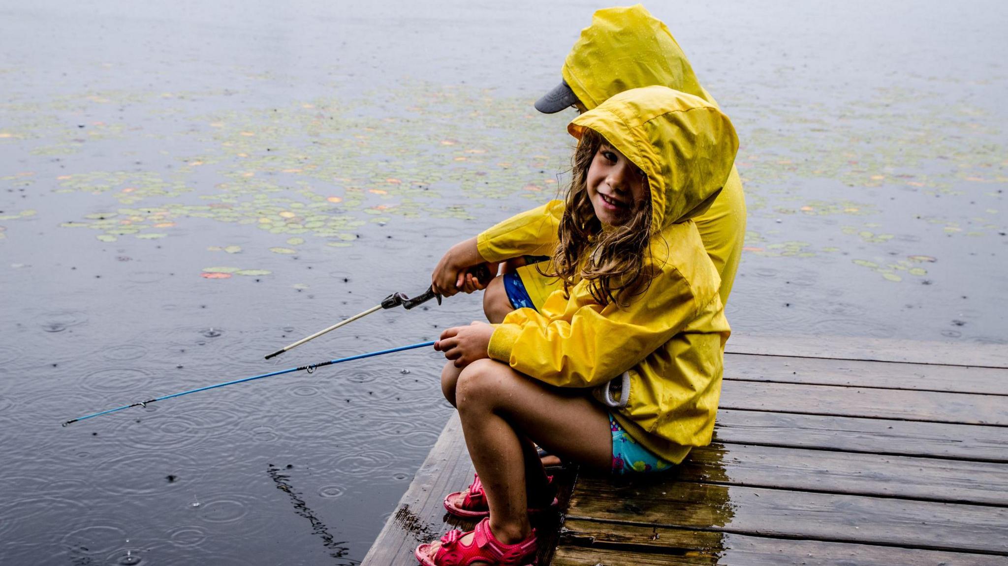 Kids fishing wearing yellow rain coats, shorts and sandals