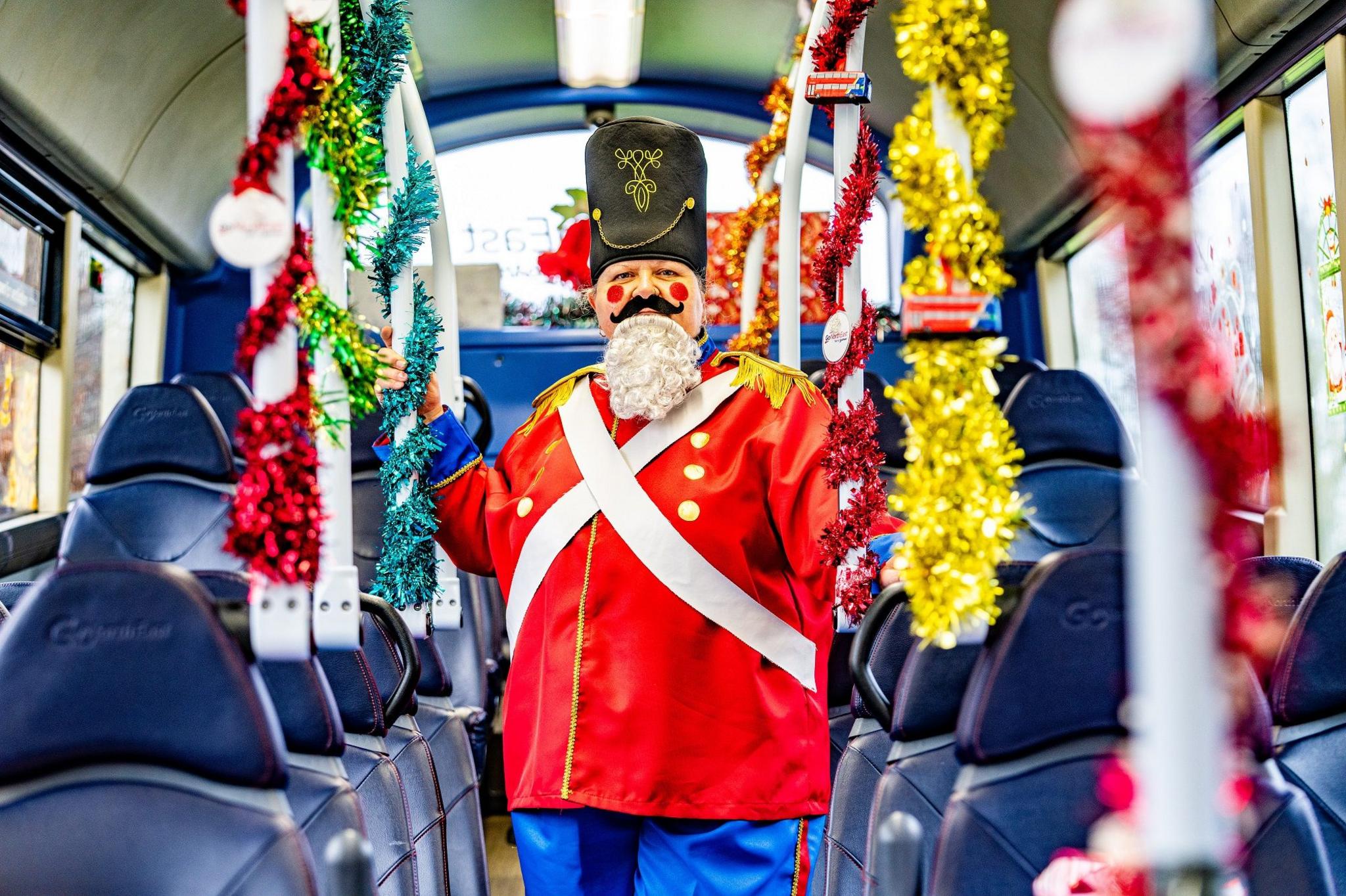 Julie Richardson standing on a bus dressed as a nutcracker soldier. She has a hat and rosy red cheeks.