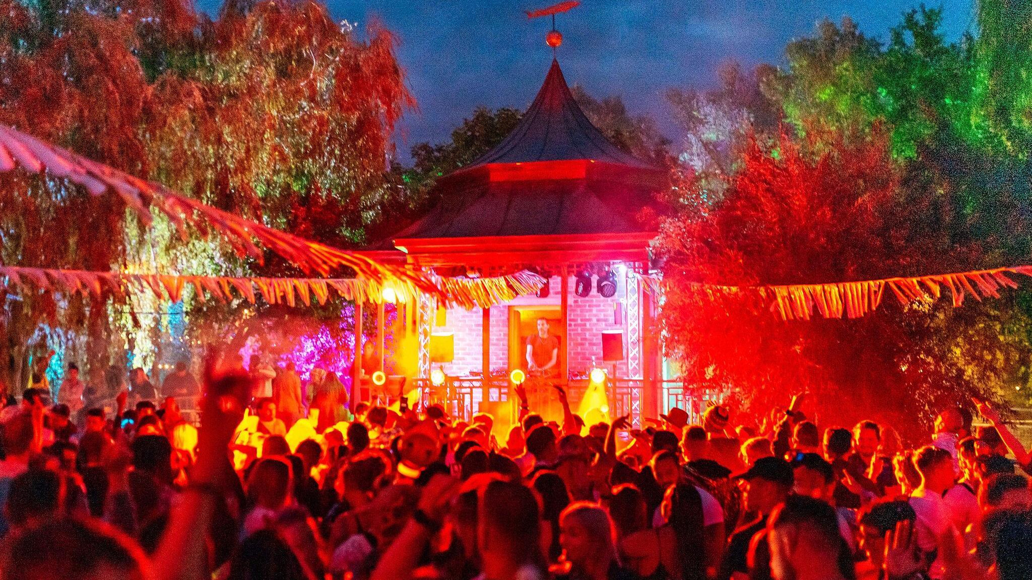 Crowds attend a small stage with a DJ playing