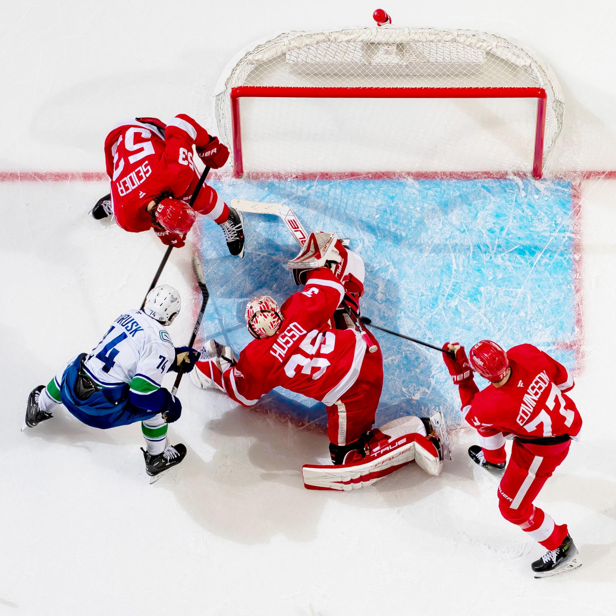 Jake DeBrusk of the Vancouver Canucks battles in front of the net with Moritz Seider of the Detroit Red Wings for the rebound on a save by Ville Husso during the third period at Little Caesars Arena in Detroit, Michigan. Vancouver defeated Detroit 5-4 in O.T.