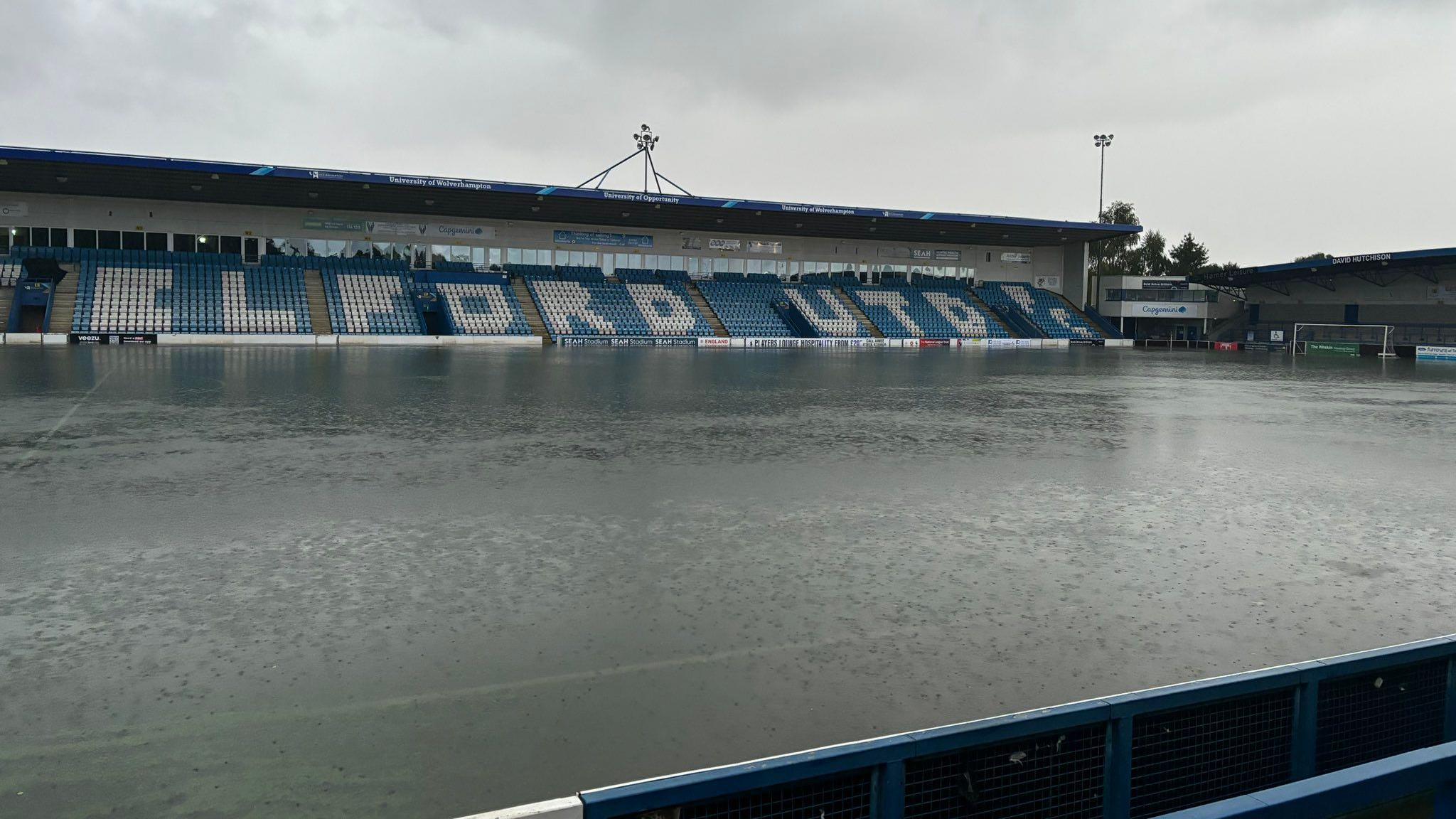 A football ground where the pitch is not visible, and is completely flooded.