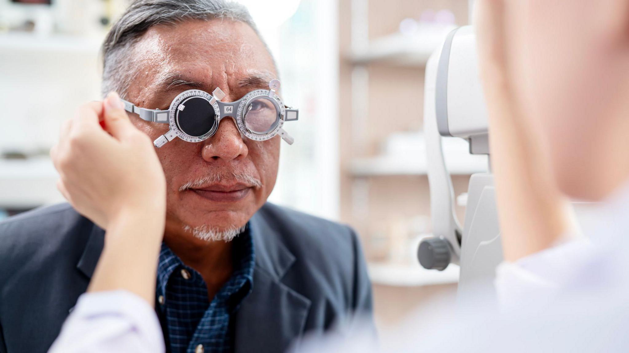 A man with short grey hair getting their eye tested.