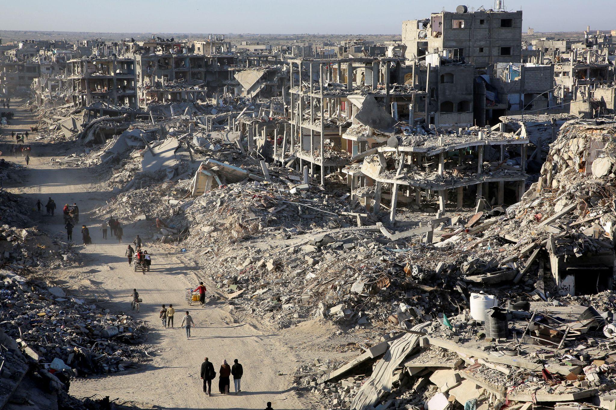 Displaced Palestinians walk past the rubble as they attempt to return to their homes in northern Gaza, on the day the ceasefire.