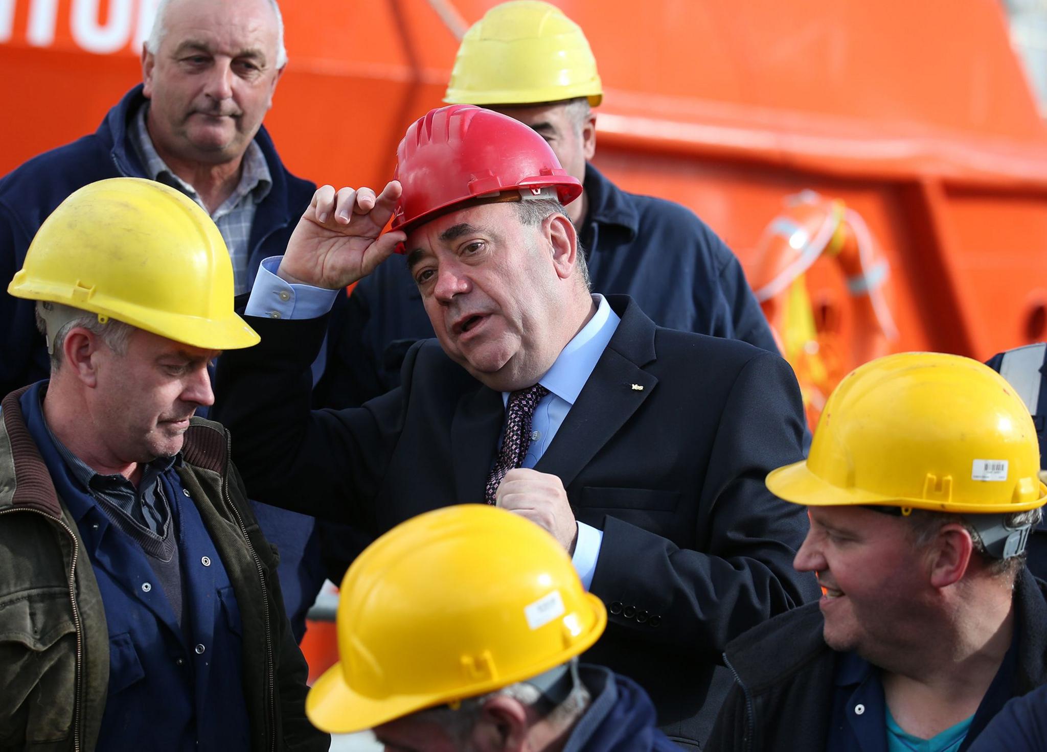 Alex Salmond wearing a red helmet, surrounded by yellow helmetted workers