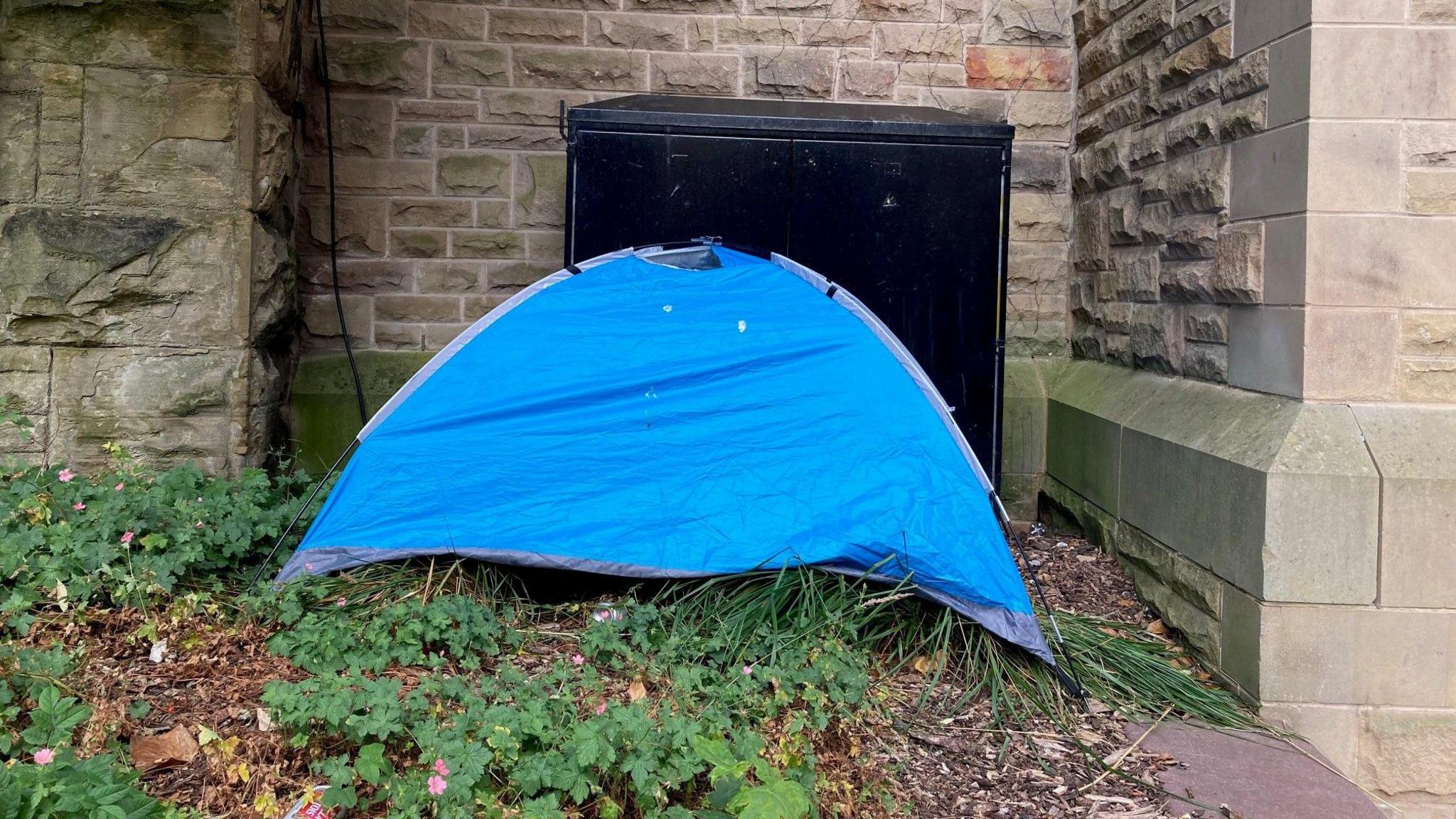 A small blue tent pitched in a flower bed in Bradford Forster Square