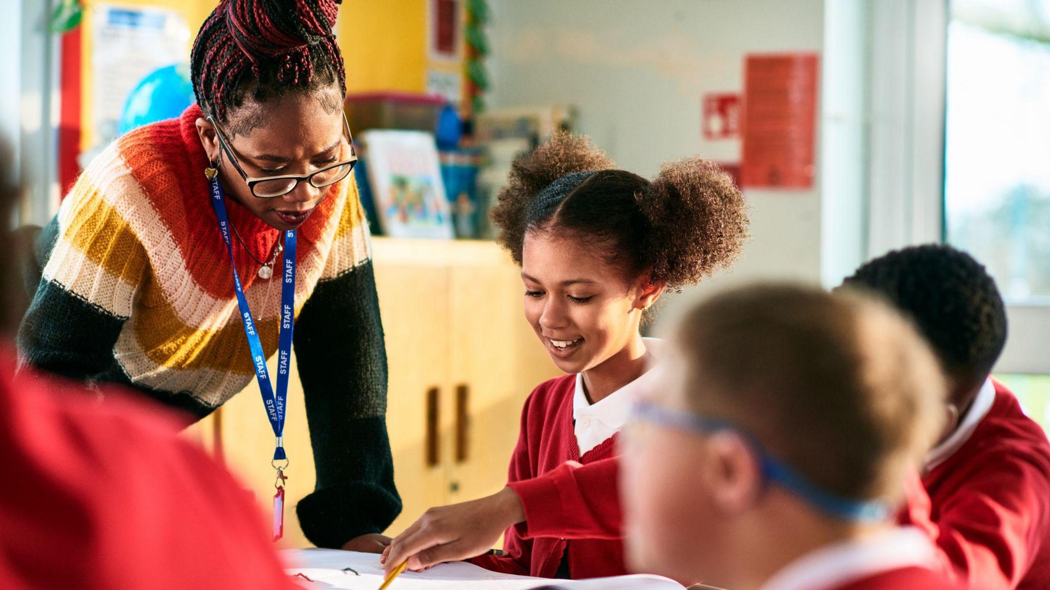 Teacher helping students at desk.