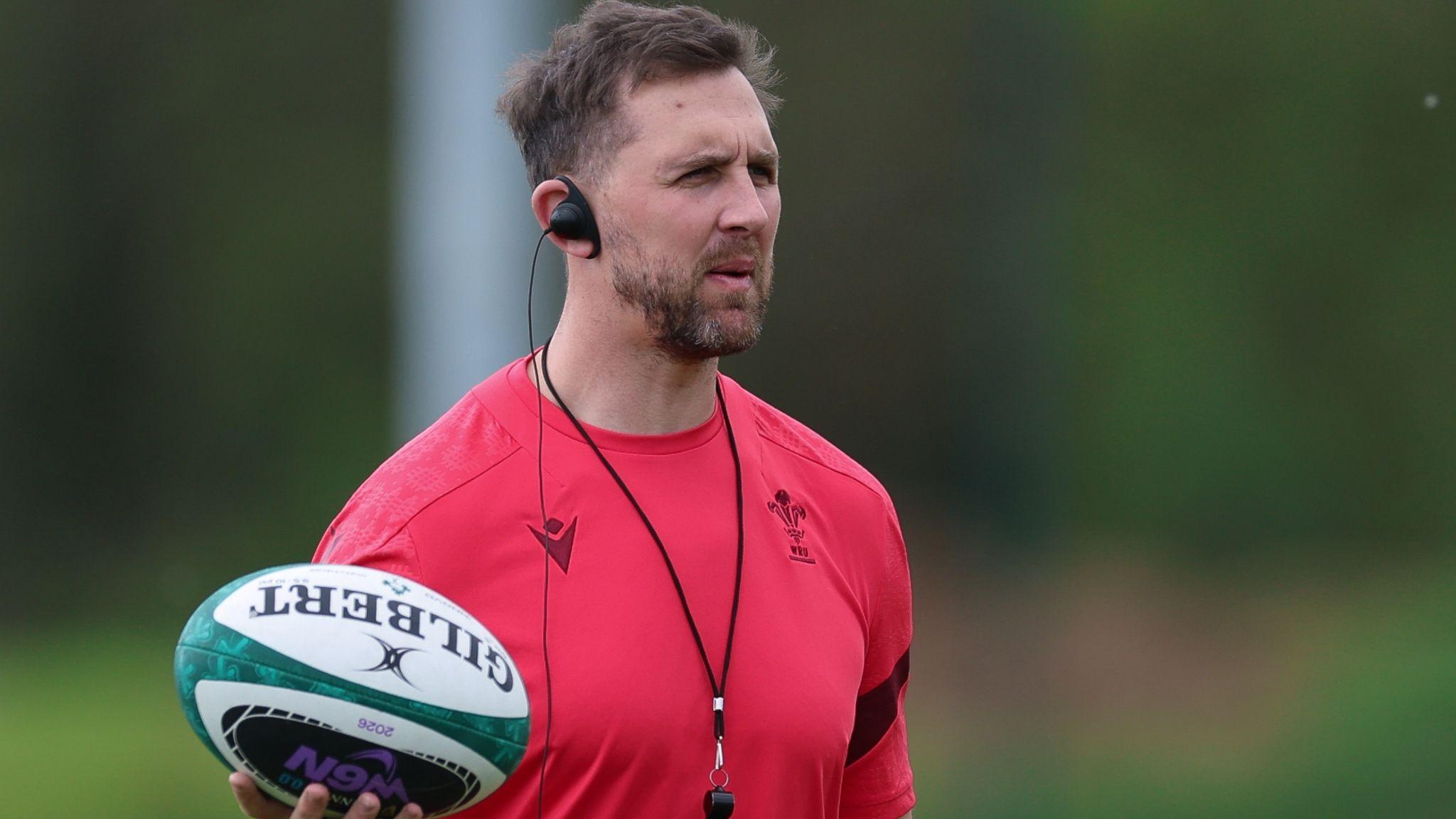 Ashley Beck in a red top at Wales training holds the ball out in his right hand
