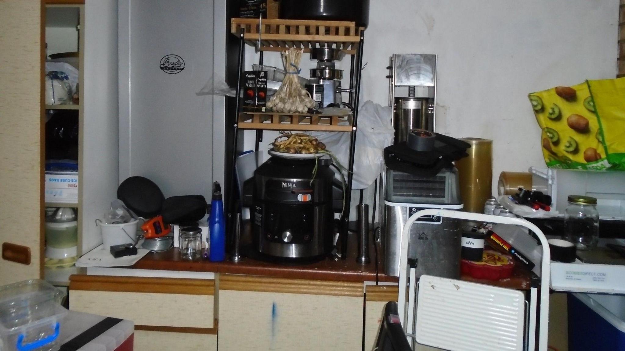 A room with kitchen cabinets, many coming open and a lot of equipment on top stacked.