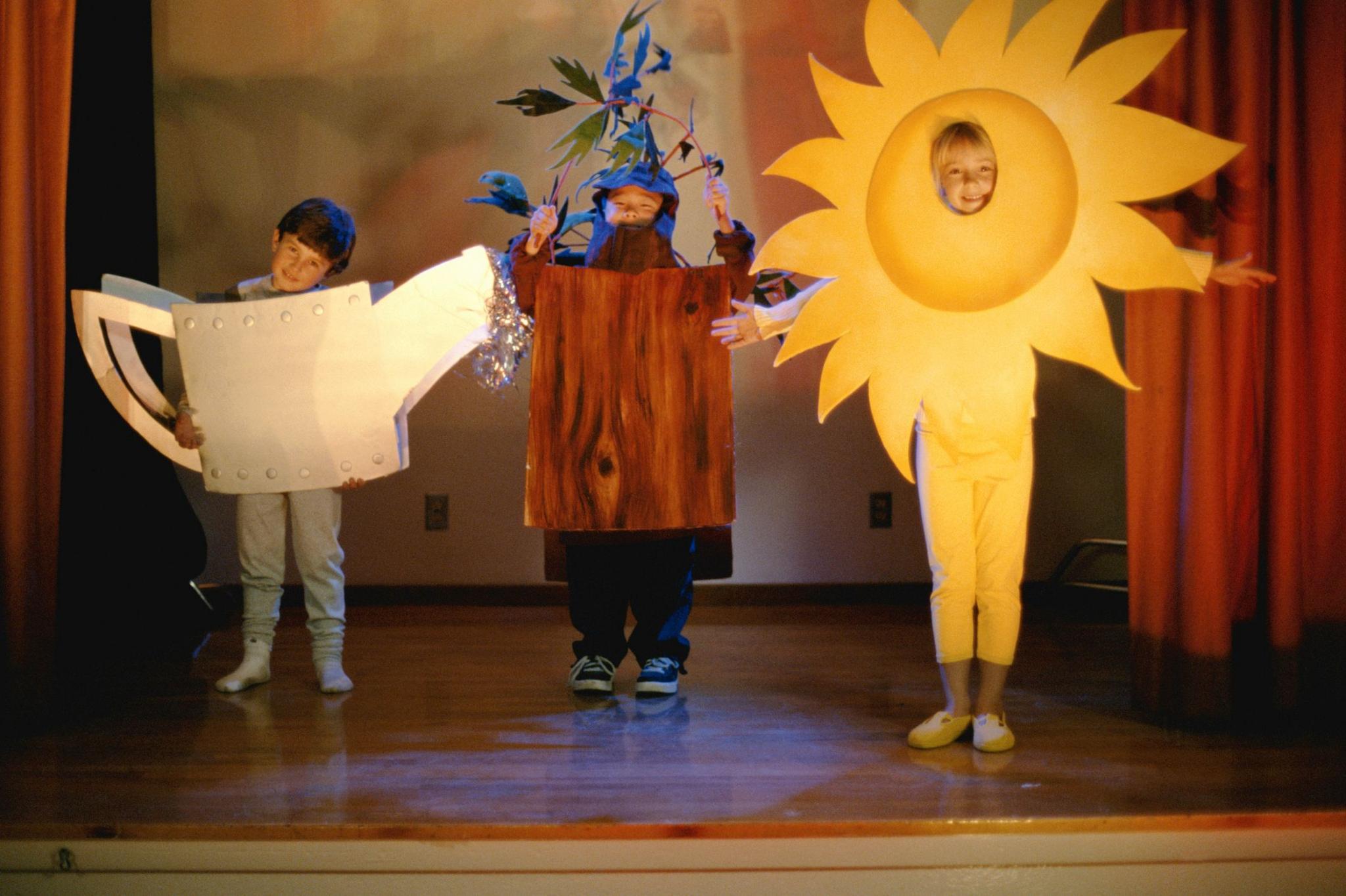 Children dressed as a watering can, tree and sun. 