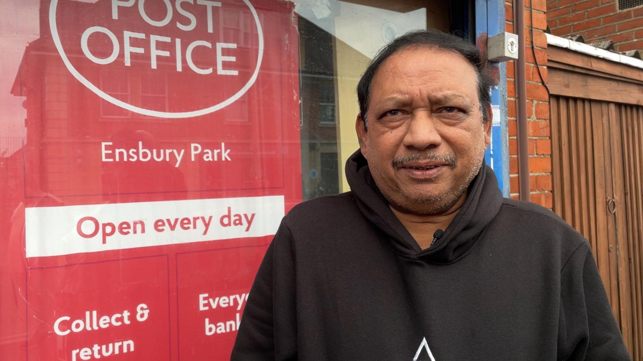 Johanson Vijayakumar, wearing a black hoodie outside a Post Office