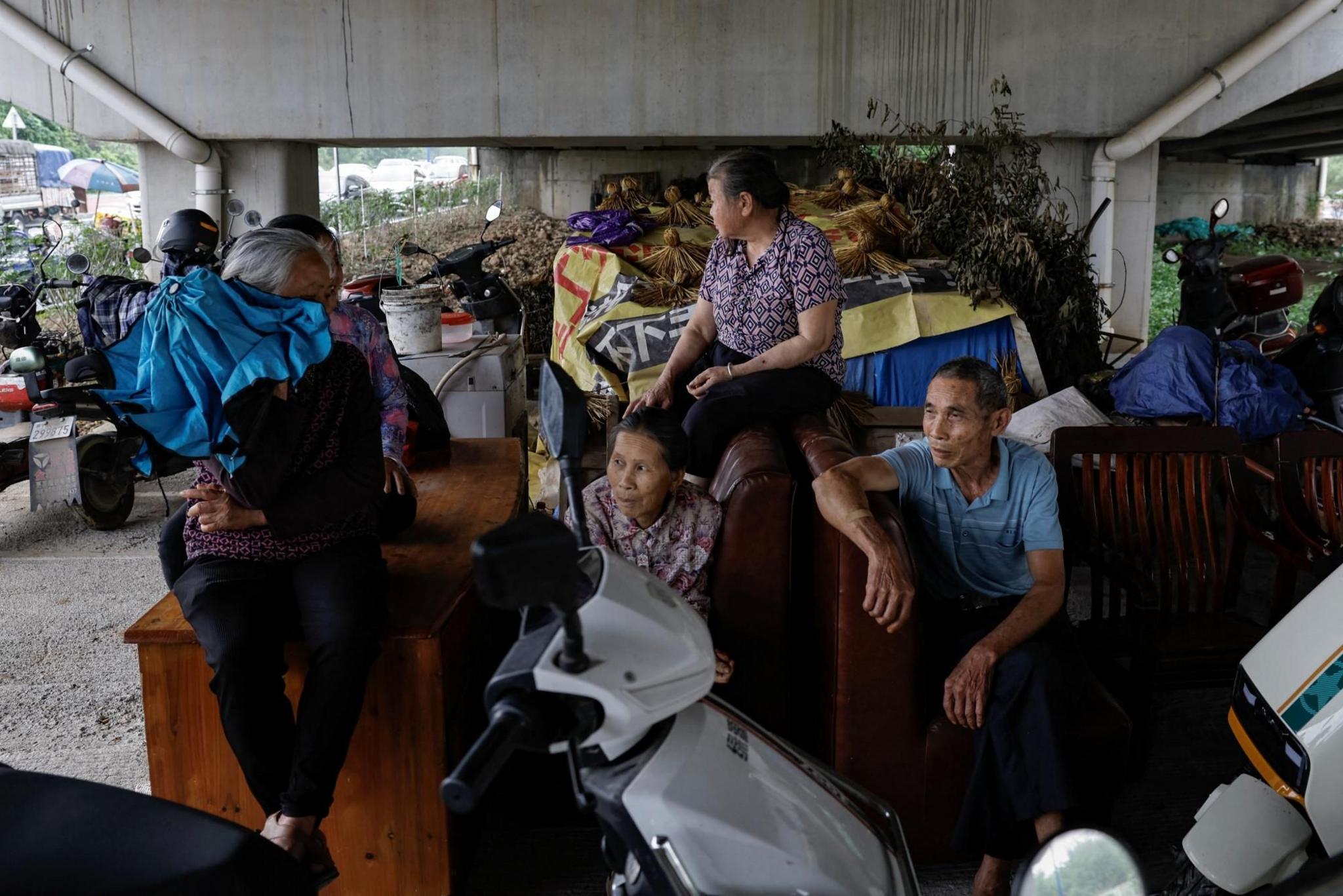 Residents from flood affected area sit at an underpass with their furniture that were moved from their houses, following heavy rainfall at a village, in Qingyuan, Guangdong province, China April 22, 2024