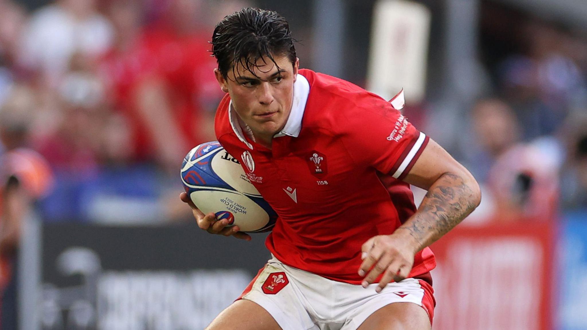 Louis Rees-Zammit in action for Wales looks determined with the ball under his arm