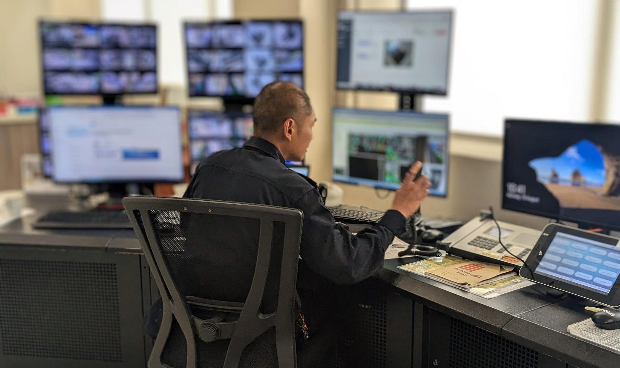 A man sitting behind a desk in the control room at the DRC