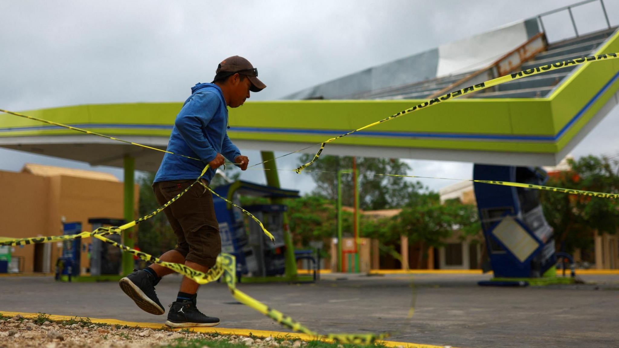 People gather beside a damaged gas station terminal