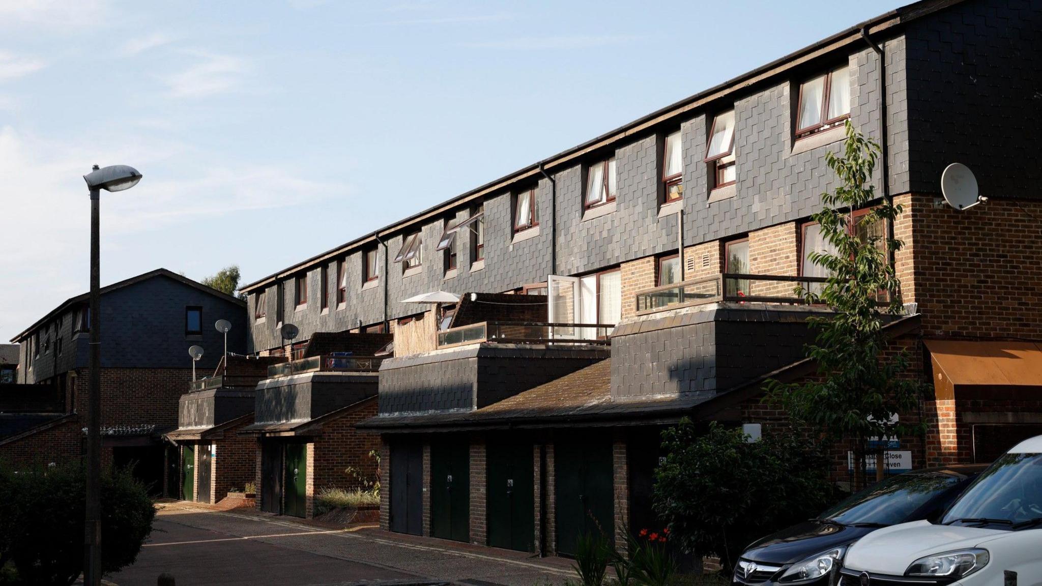 A row of homes on the estate with grey tiles and four balconies. 