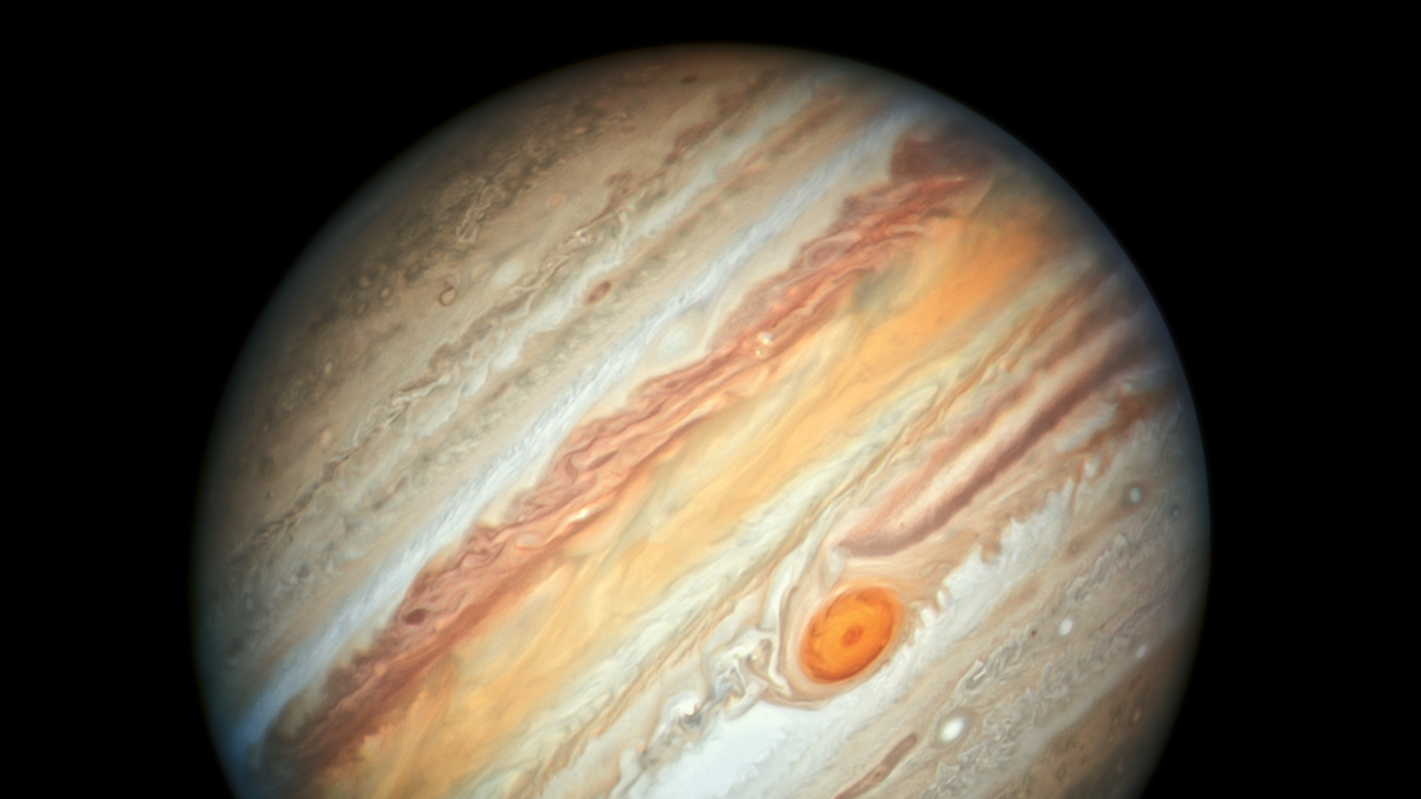 A photo of Jupiter, a beige planet with yellow and brown streaks, taken by the Hubble telescope