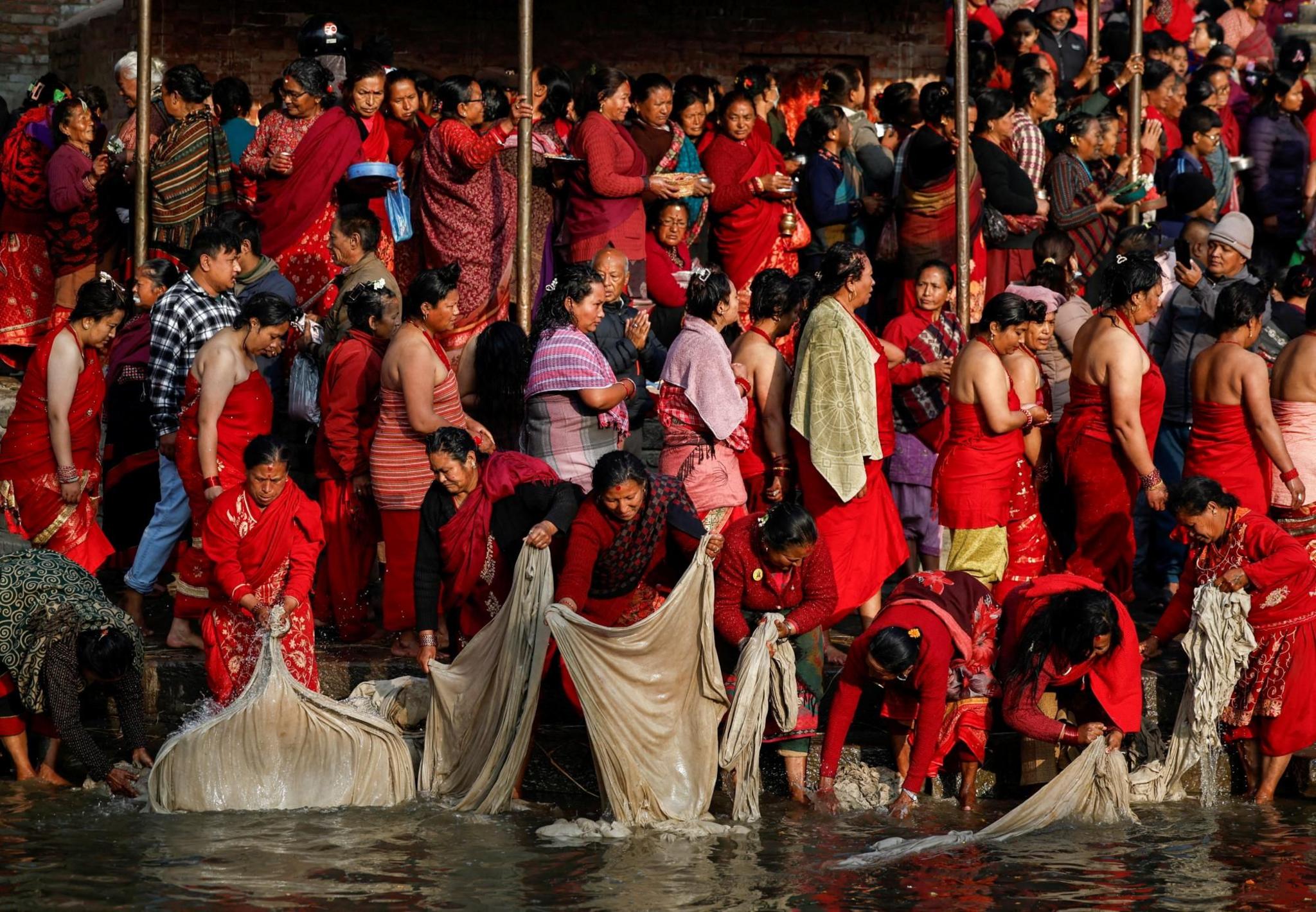 Women dressed in red wash clothes in a river